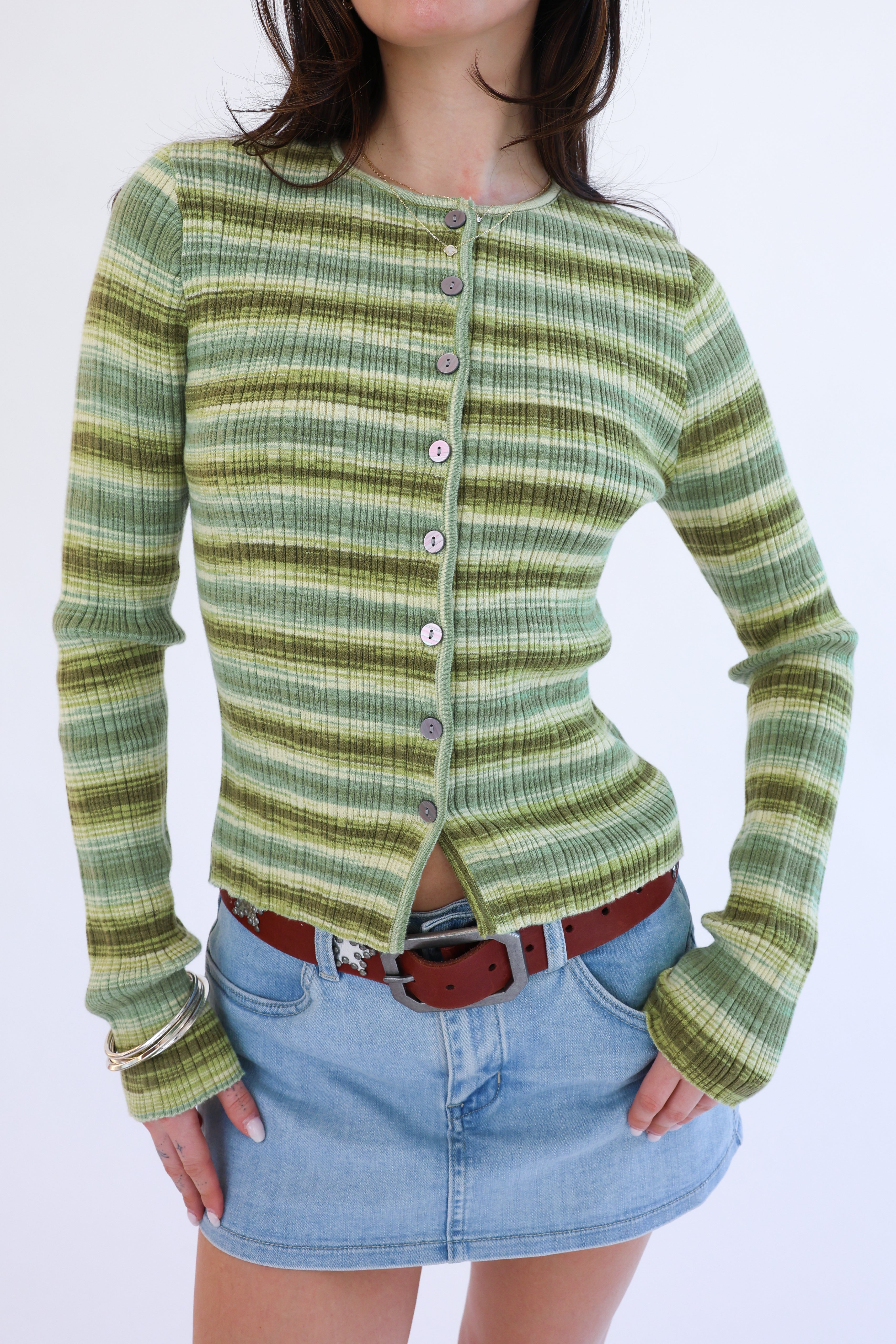 Person wearing a green plaid cardigan over a denim skirt on a white background