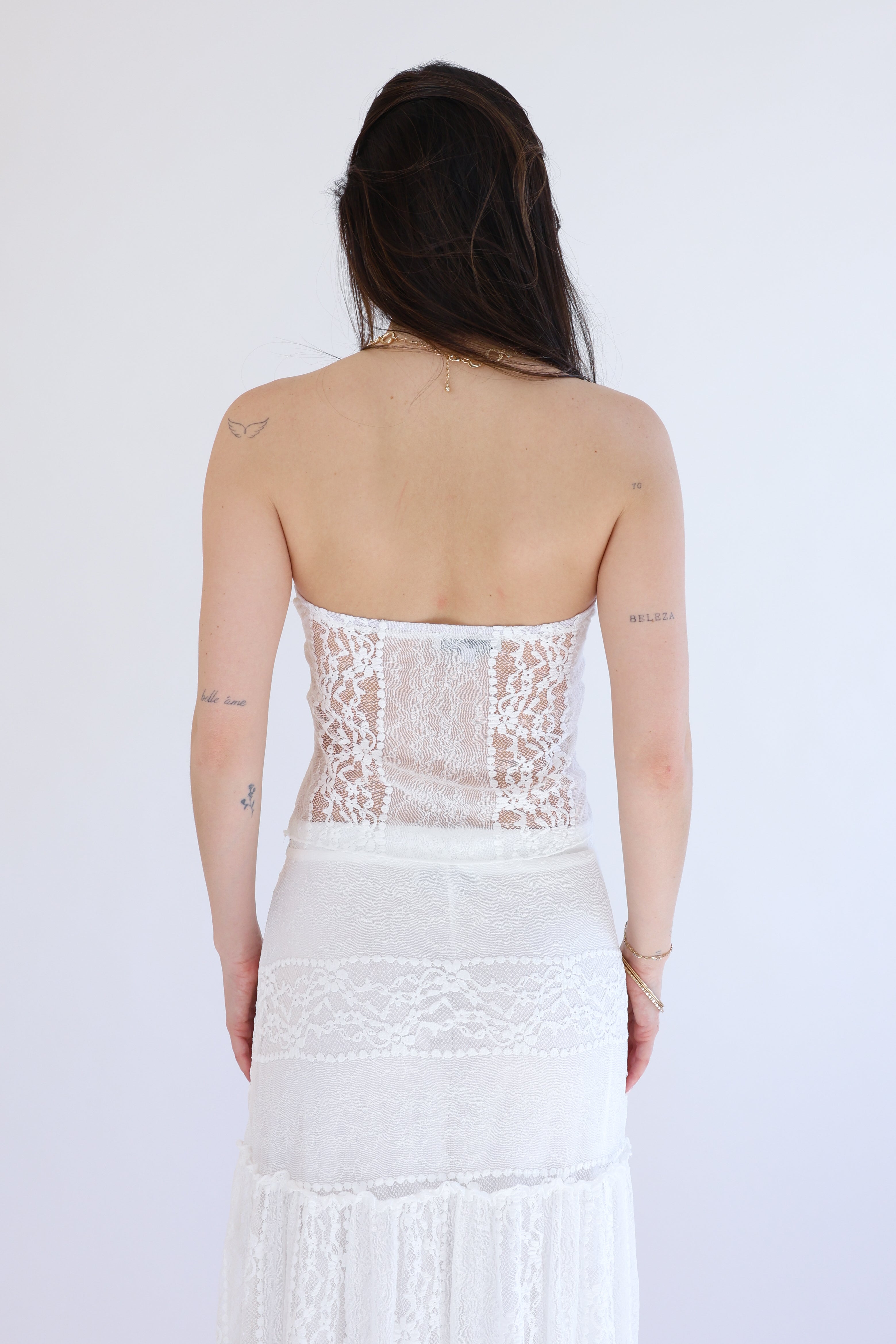 Person wearing a white lace dress with a plain background