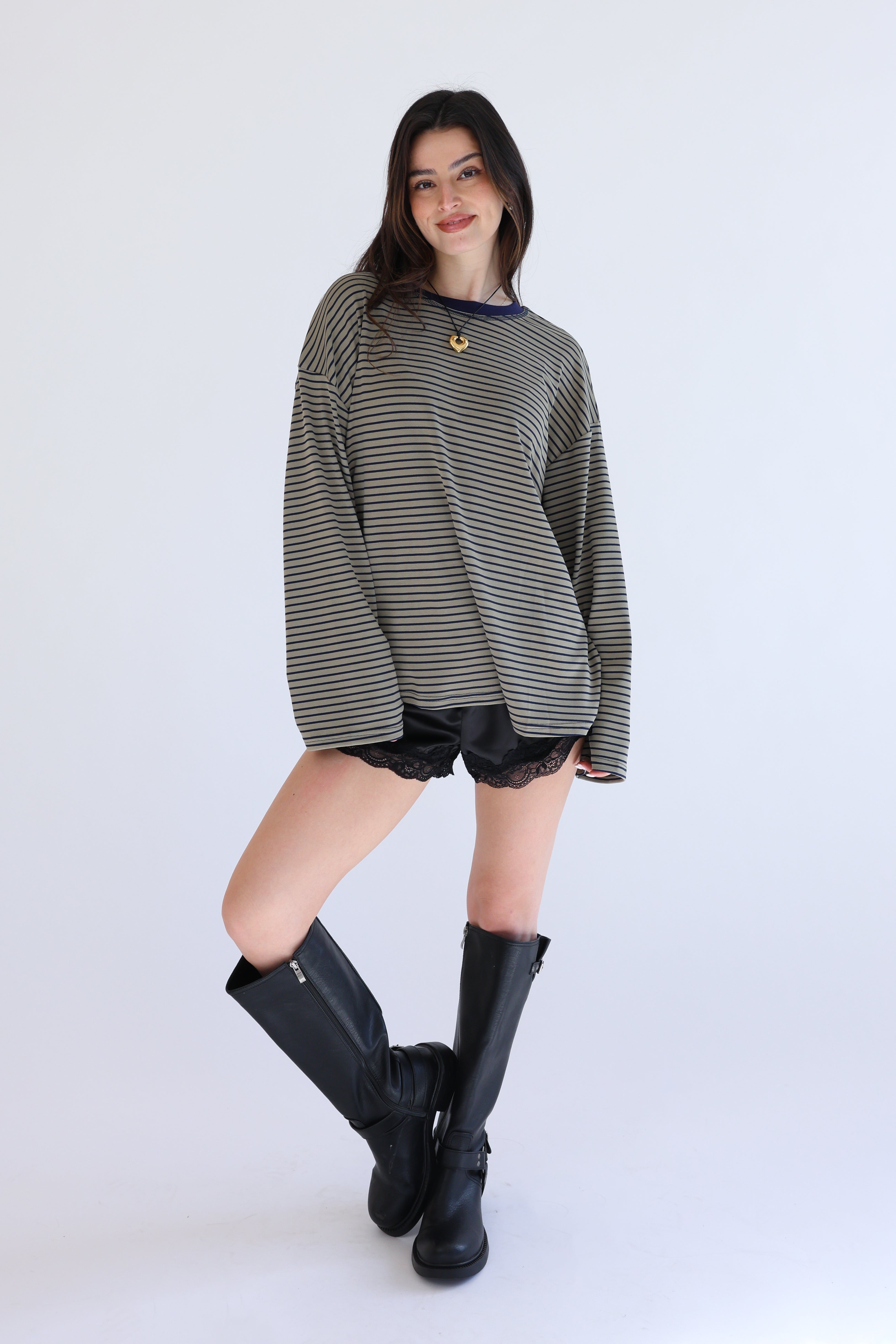 Woman wearing a striped sweater, black shorts, and black rain boots on a white background