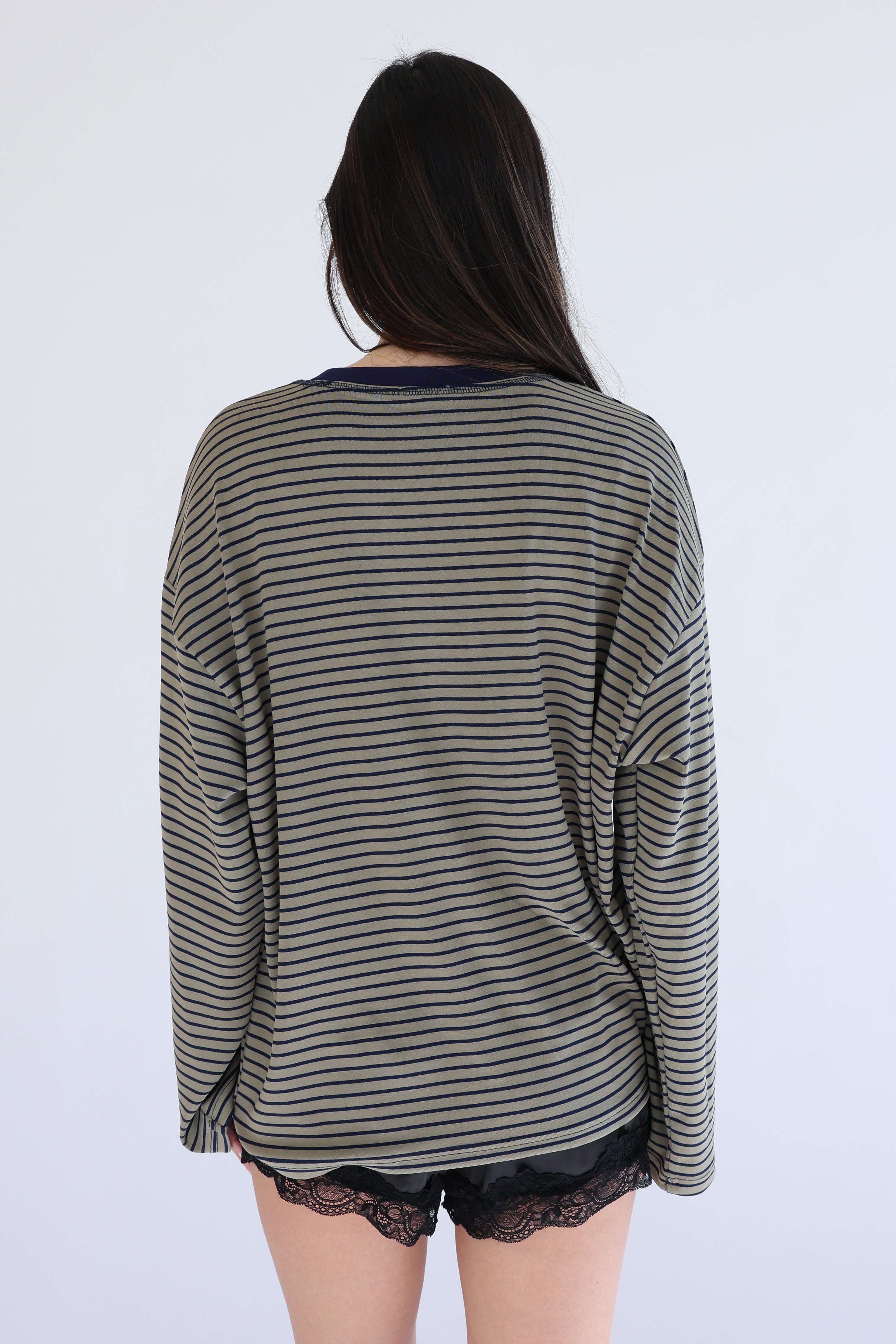 Person wearing a striped long-sleeve top and black lace underwear on a white background