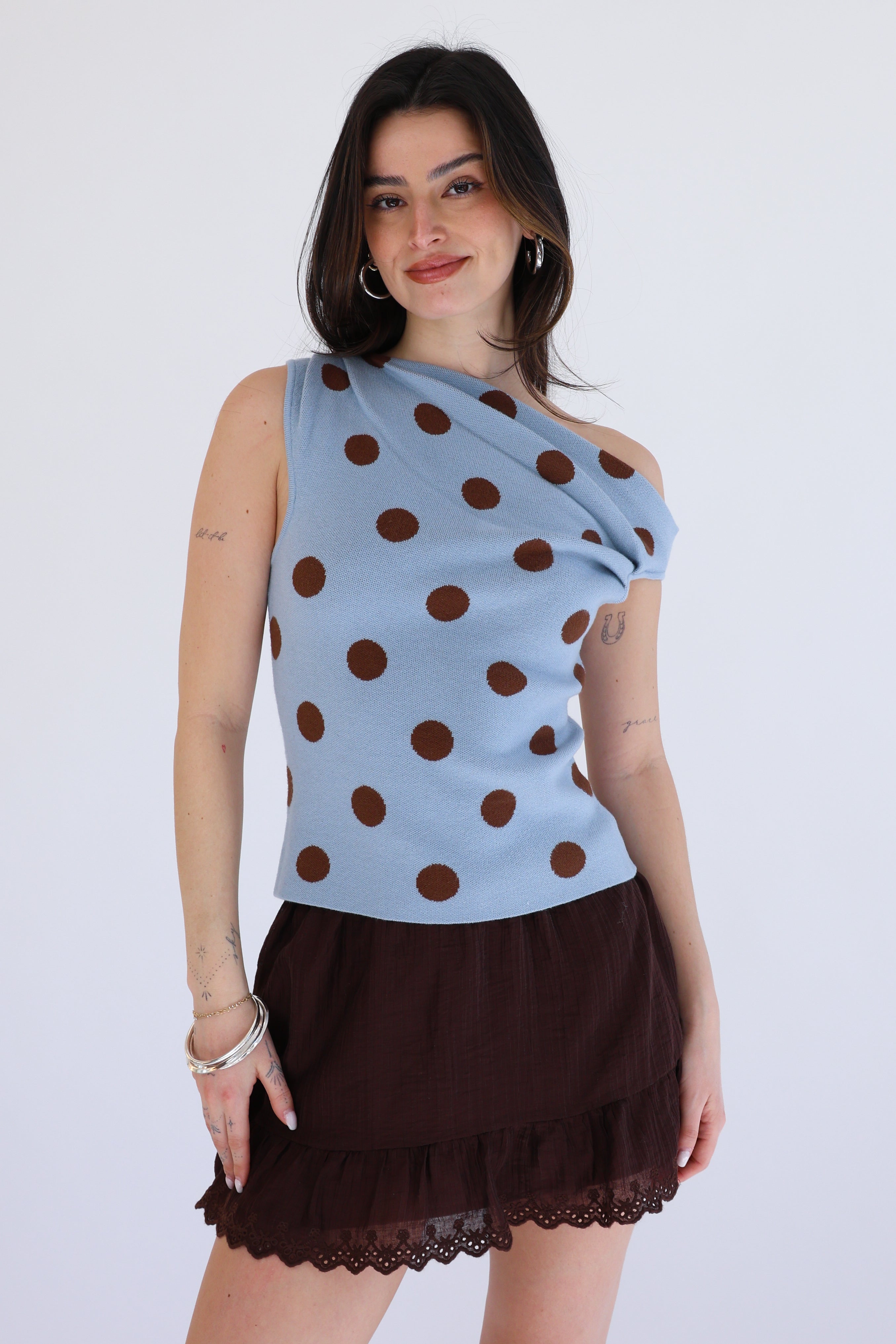 Woman wearing a blue top with brown polka dots and a brown skirt on a white background