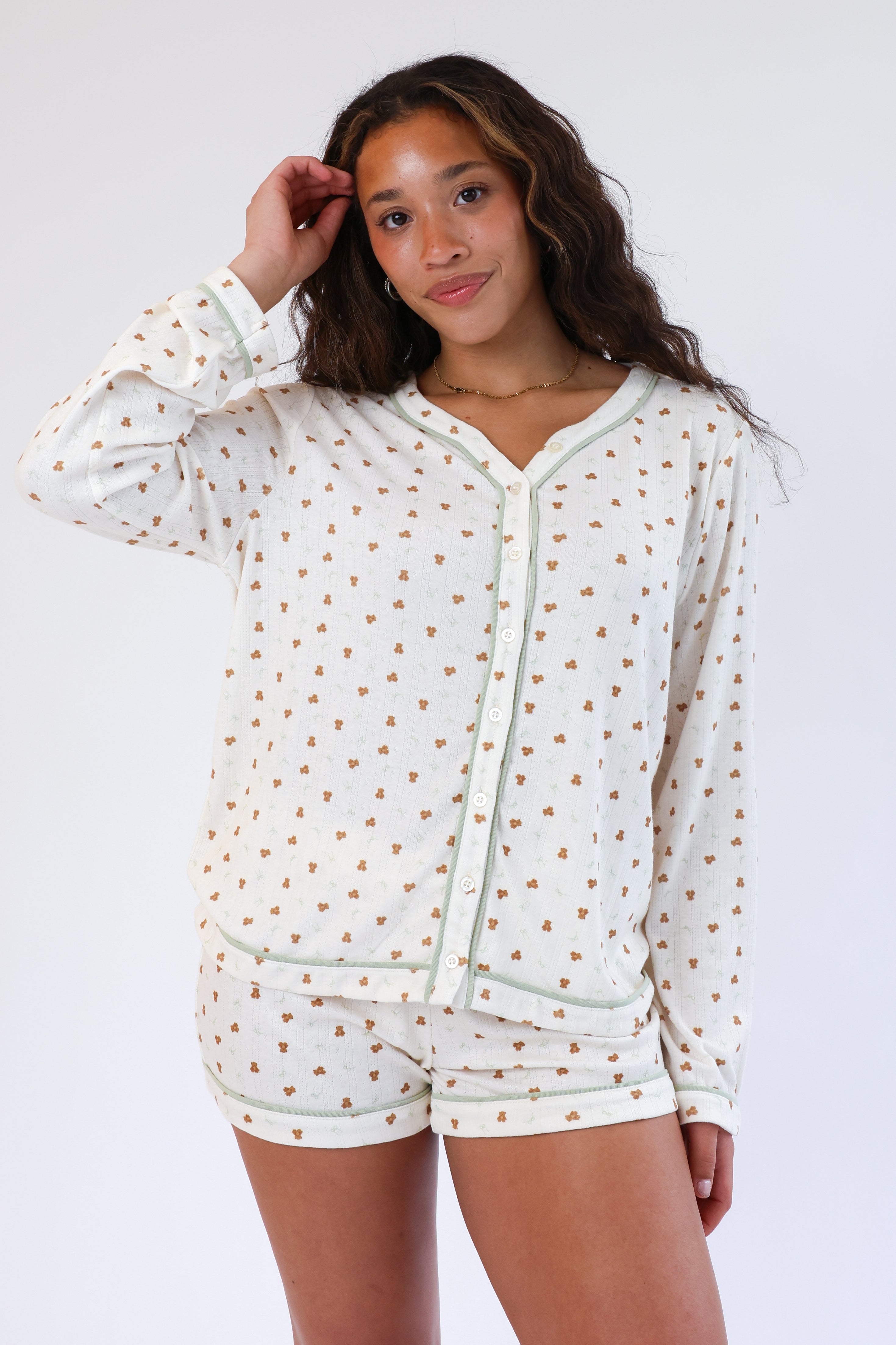 Woman wearing a white hoodie with gold polka dots and matching shorts on a white background
