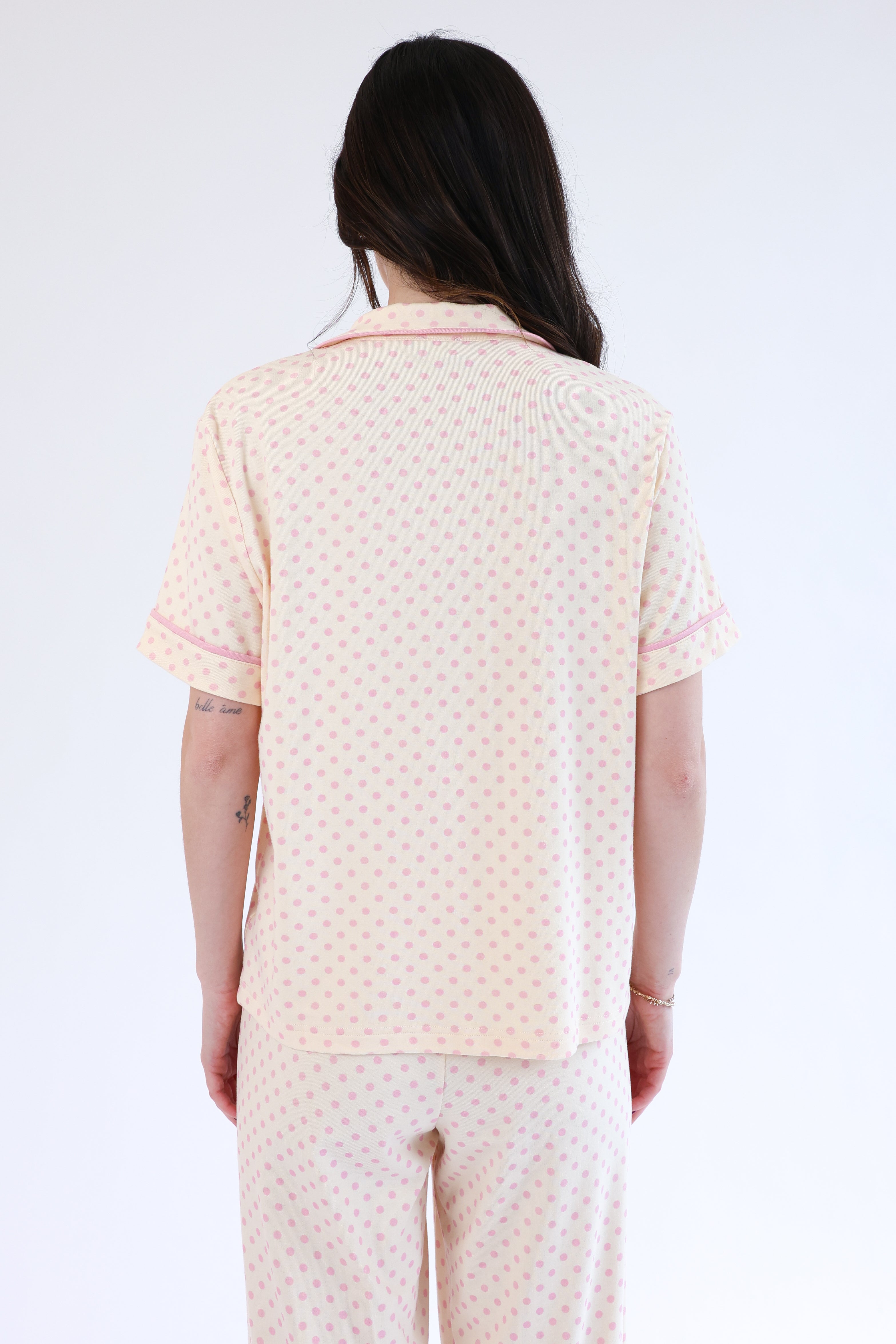 Person wearing a light-colored polka dot outfit on a white background