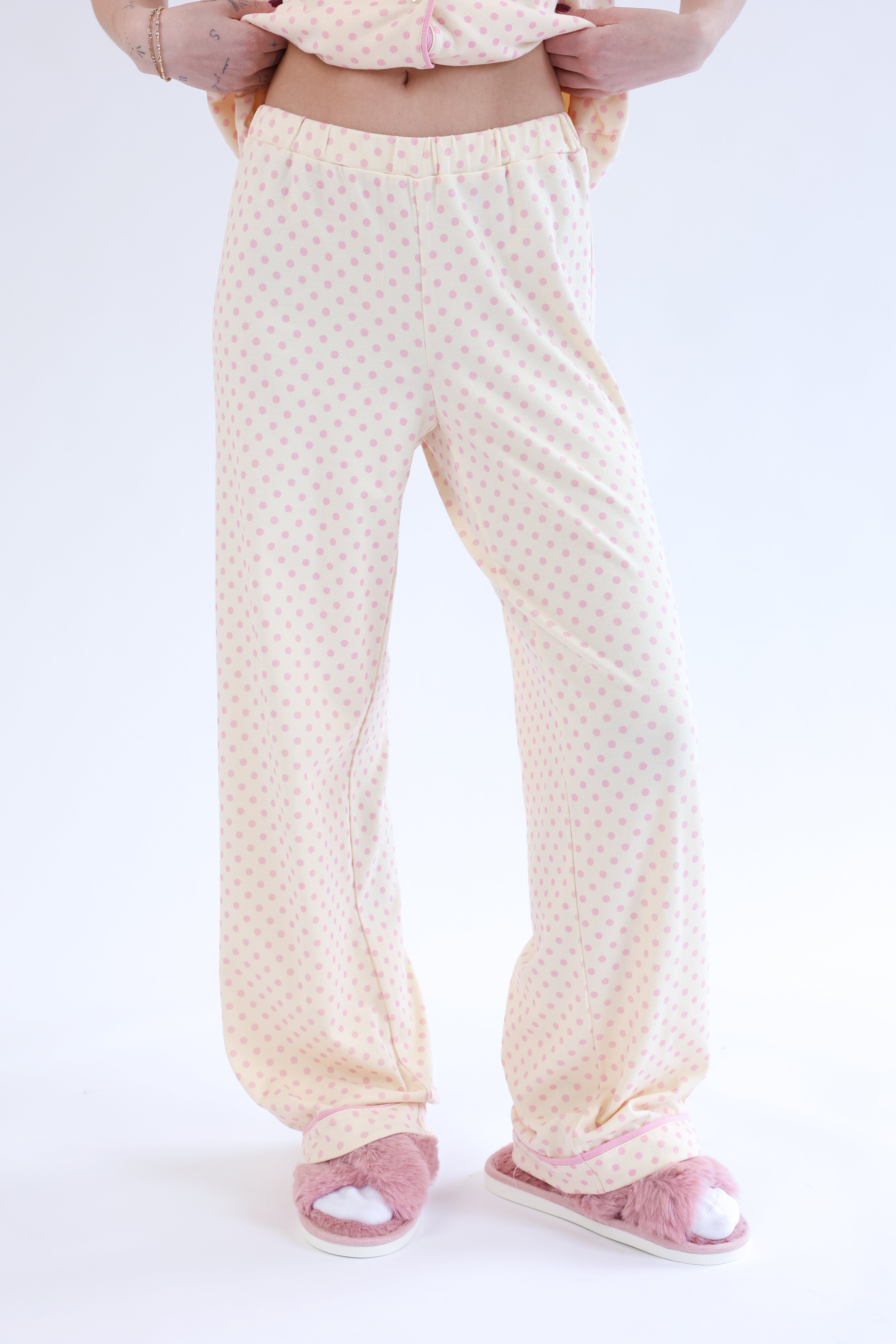Person wearing light-colored pajama pants and pink socks on a white background