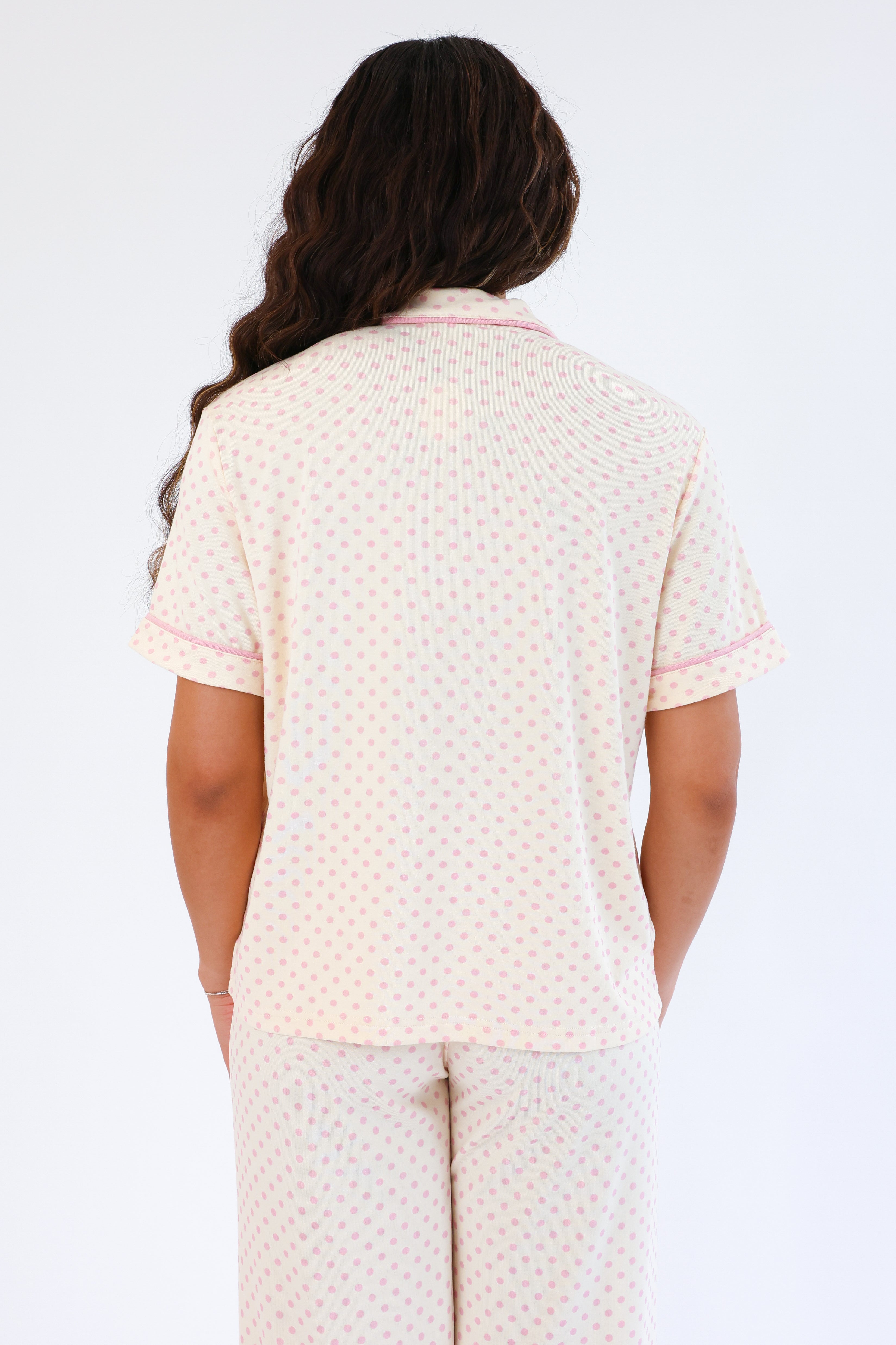 Person wearing a cream-colored pajama set with a subtle pattern on a white background