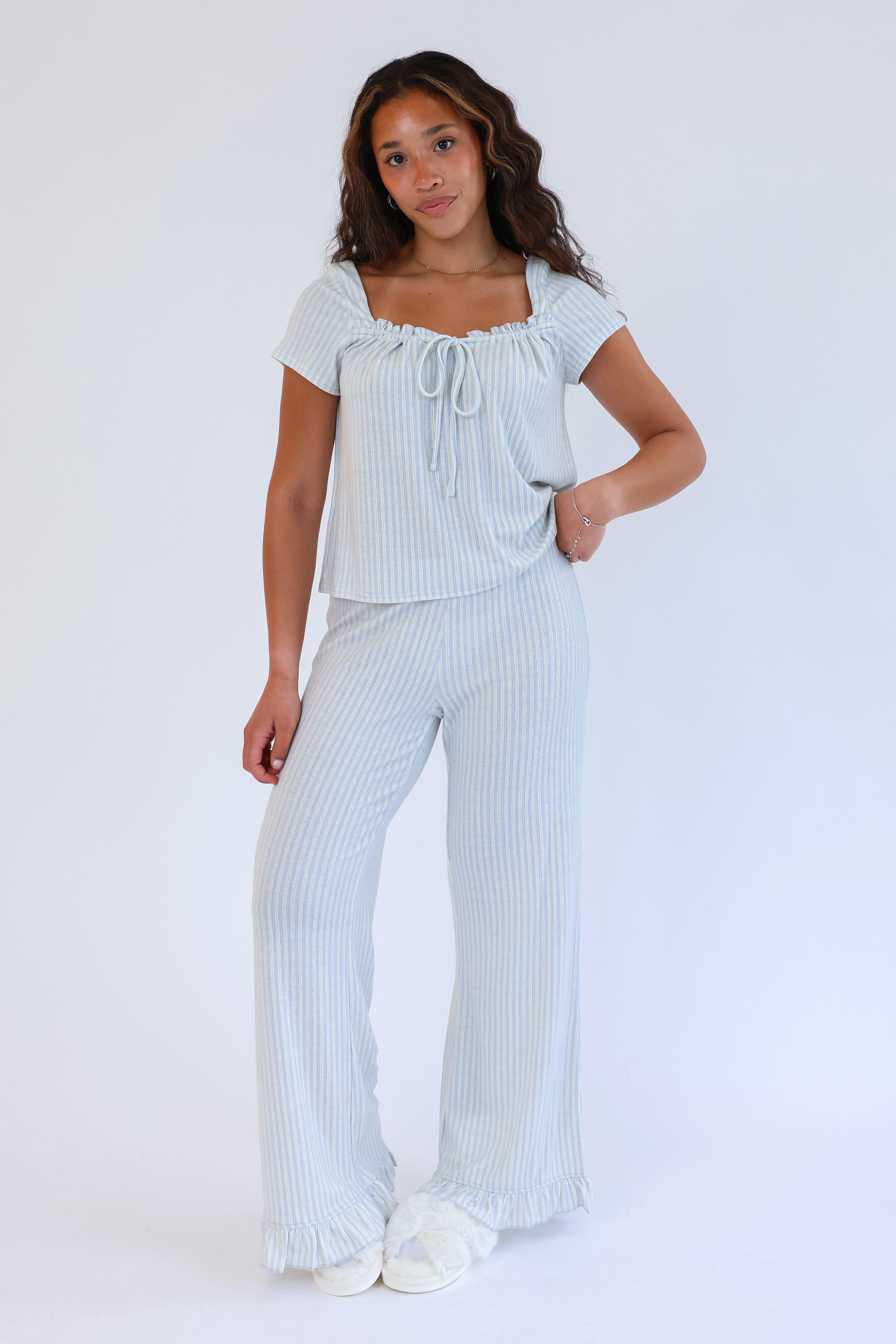 Woman wearing a light blue pajama set with a white background