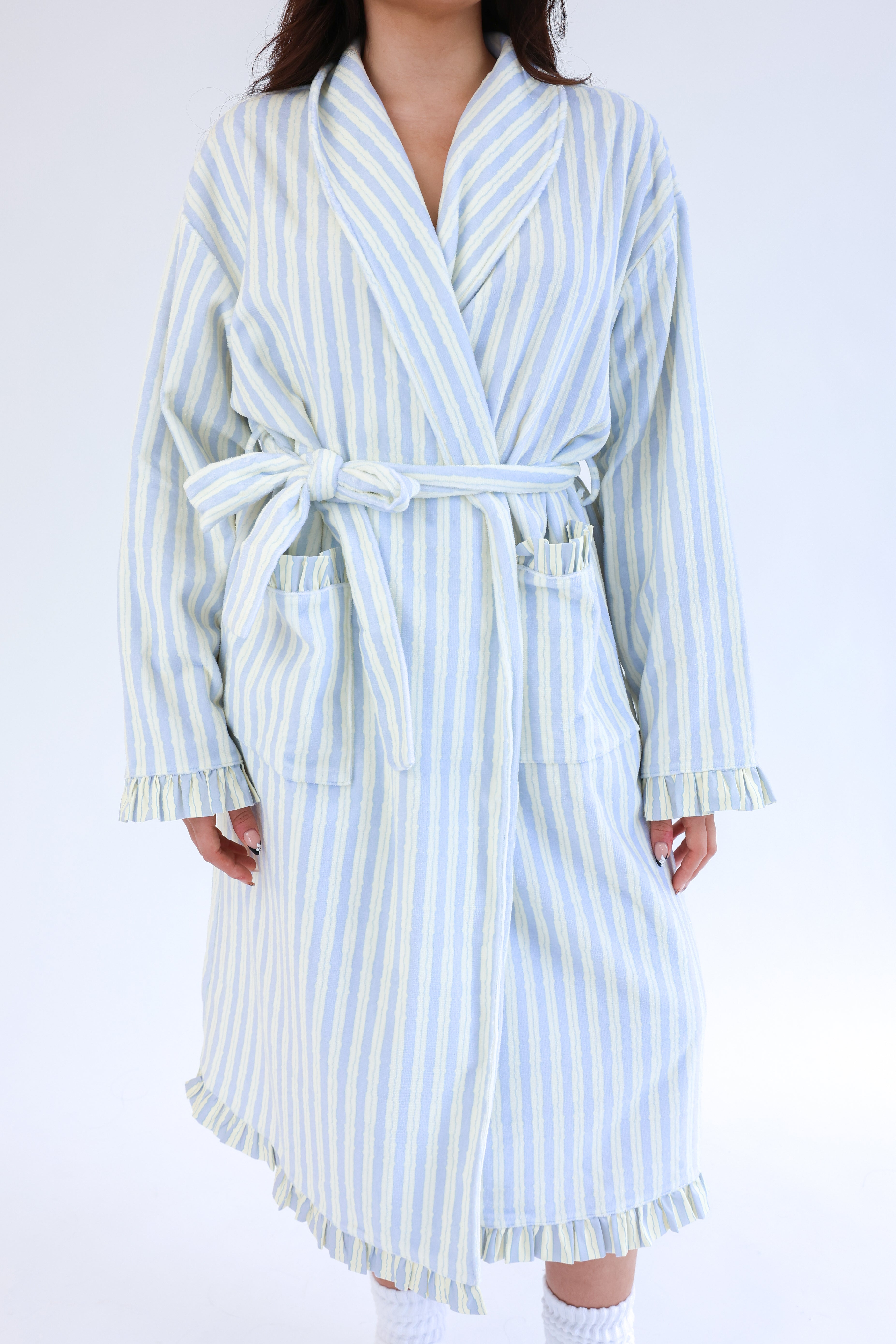 Person wearing a light blue and white striped robe on a plain background