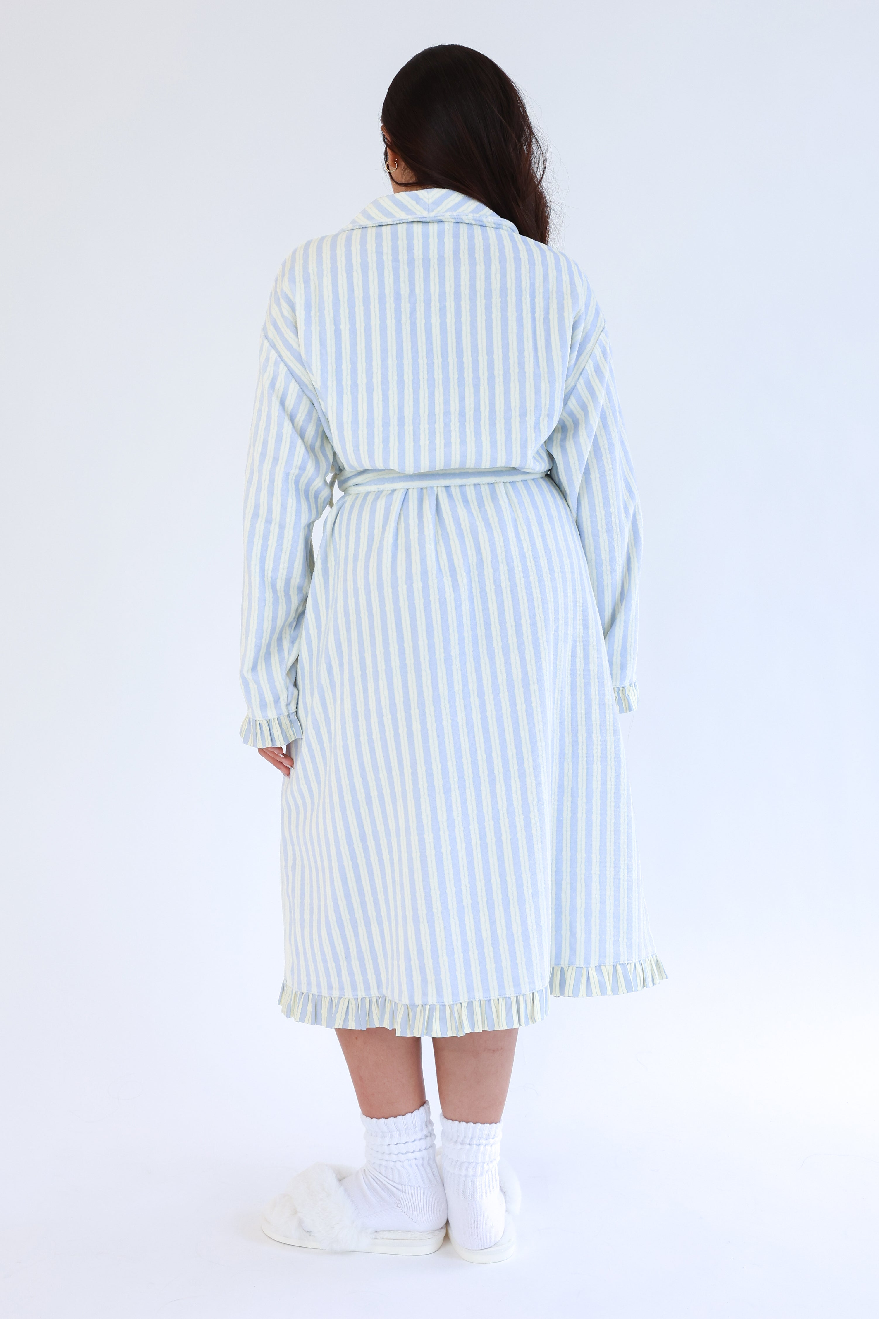 Person wearing a light blue and white striped robe on a white background