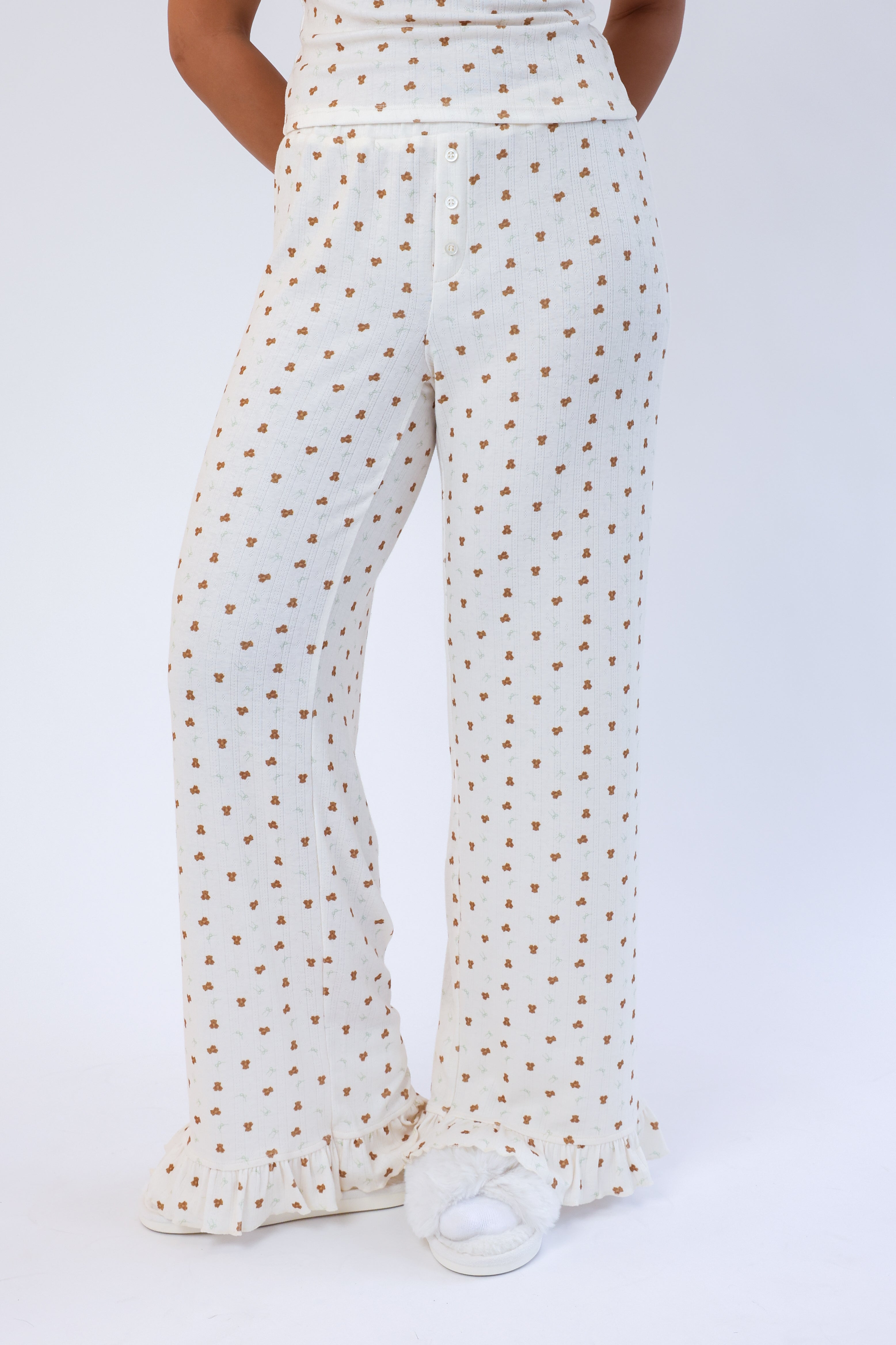 White pants with small gold patterns worn by a person on a white background