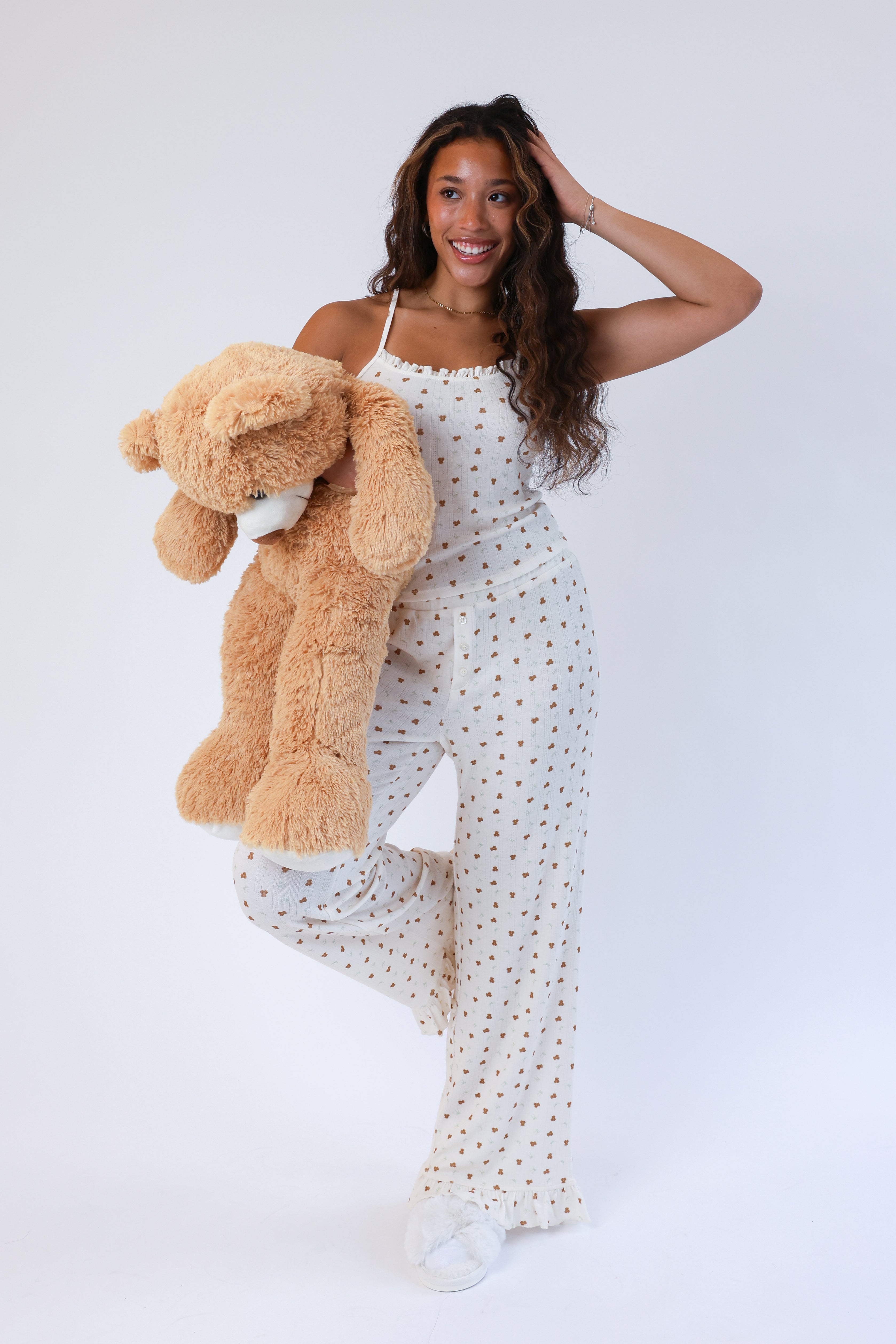 Woman in a polka dot dress holding a teddy bear against a white background