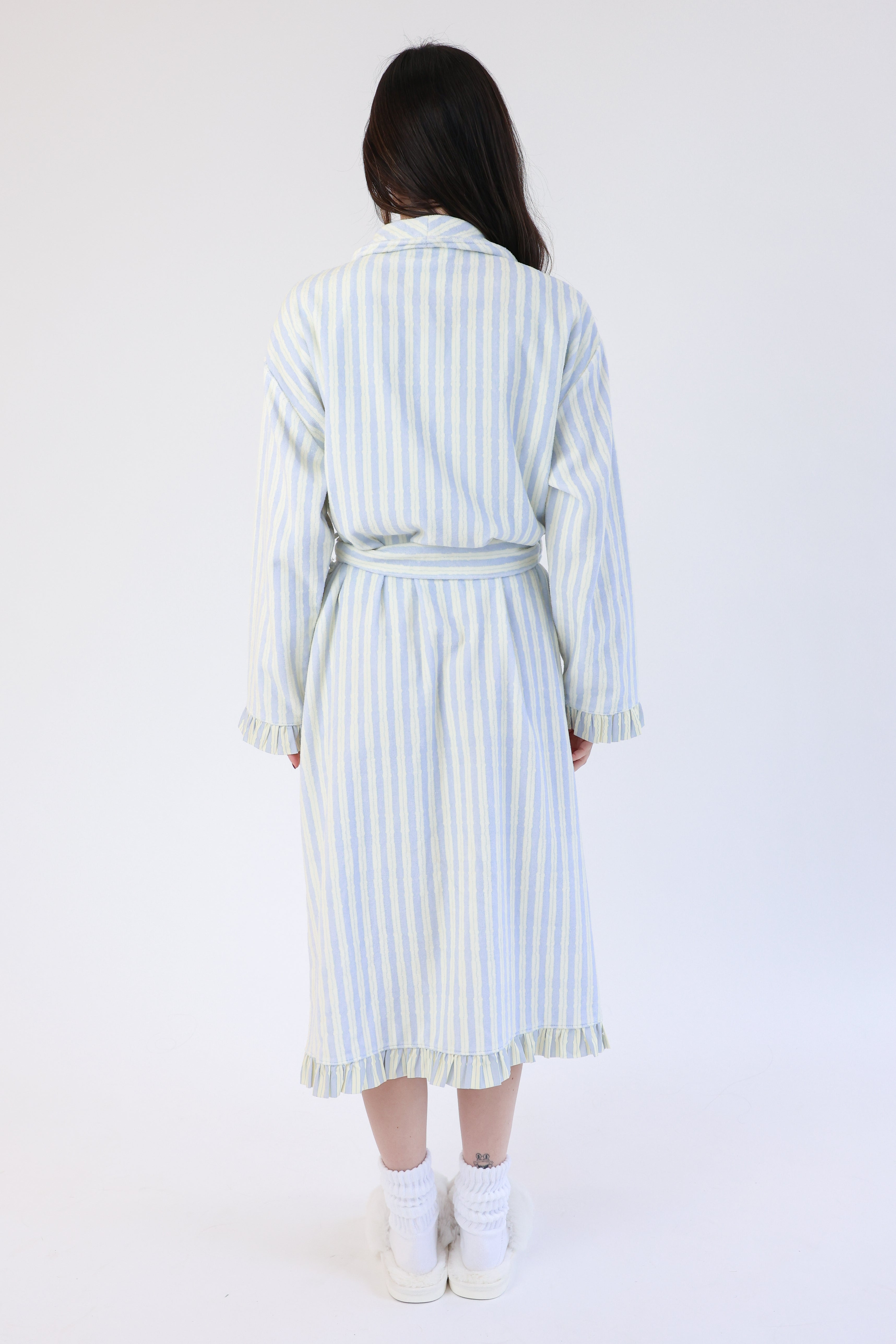 Woman wearing a light blue and white striped dress with a belt on a white background