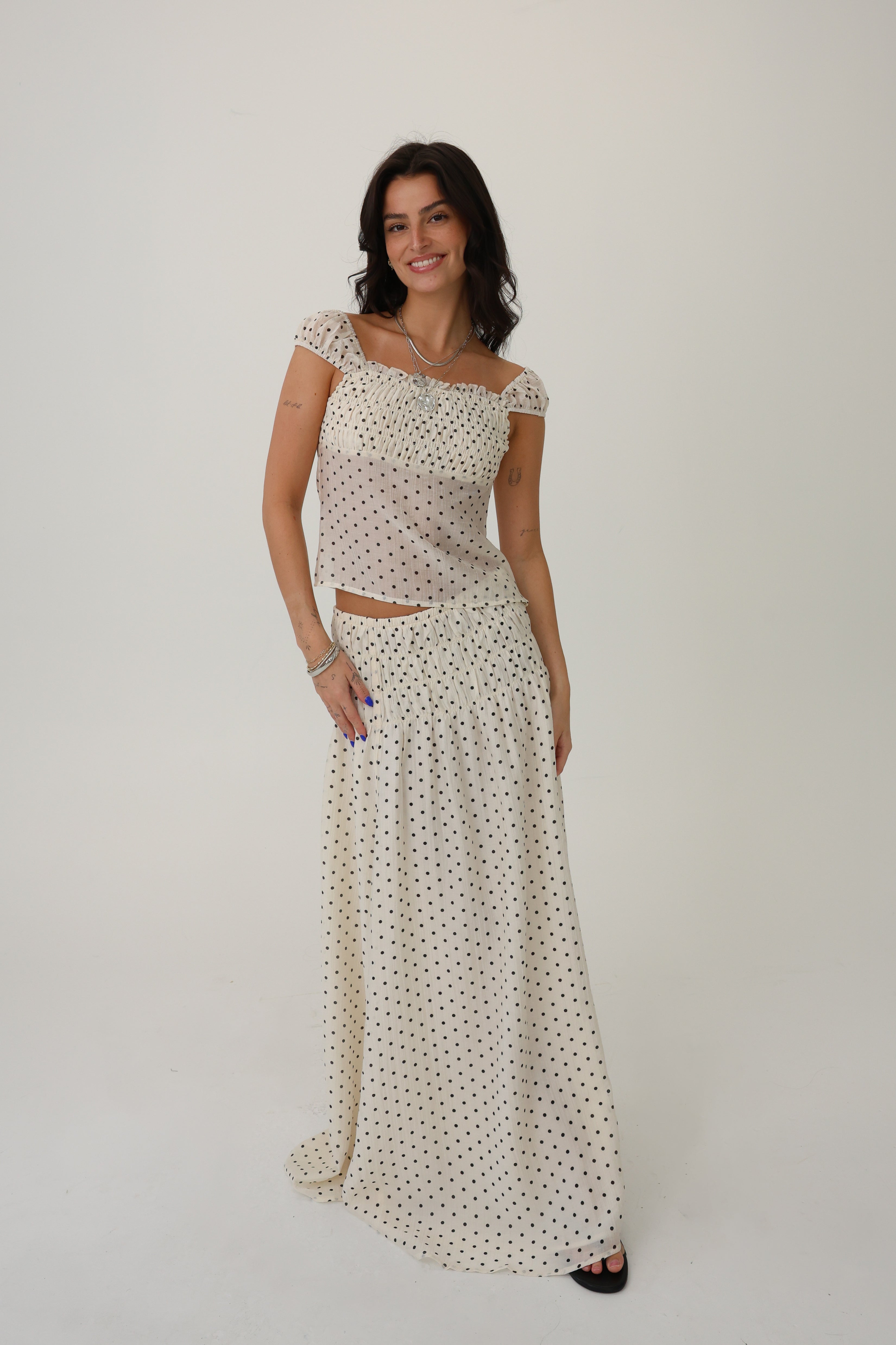 Woman wearing a polka dot top and skirt set on a plain background