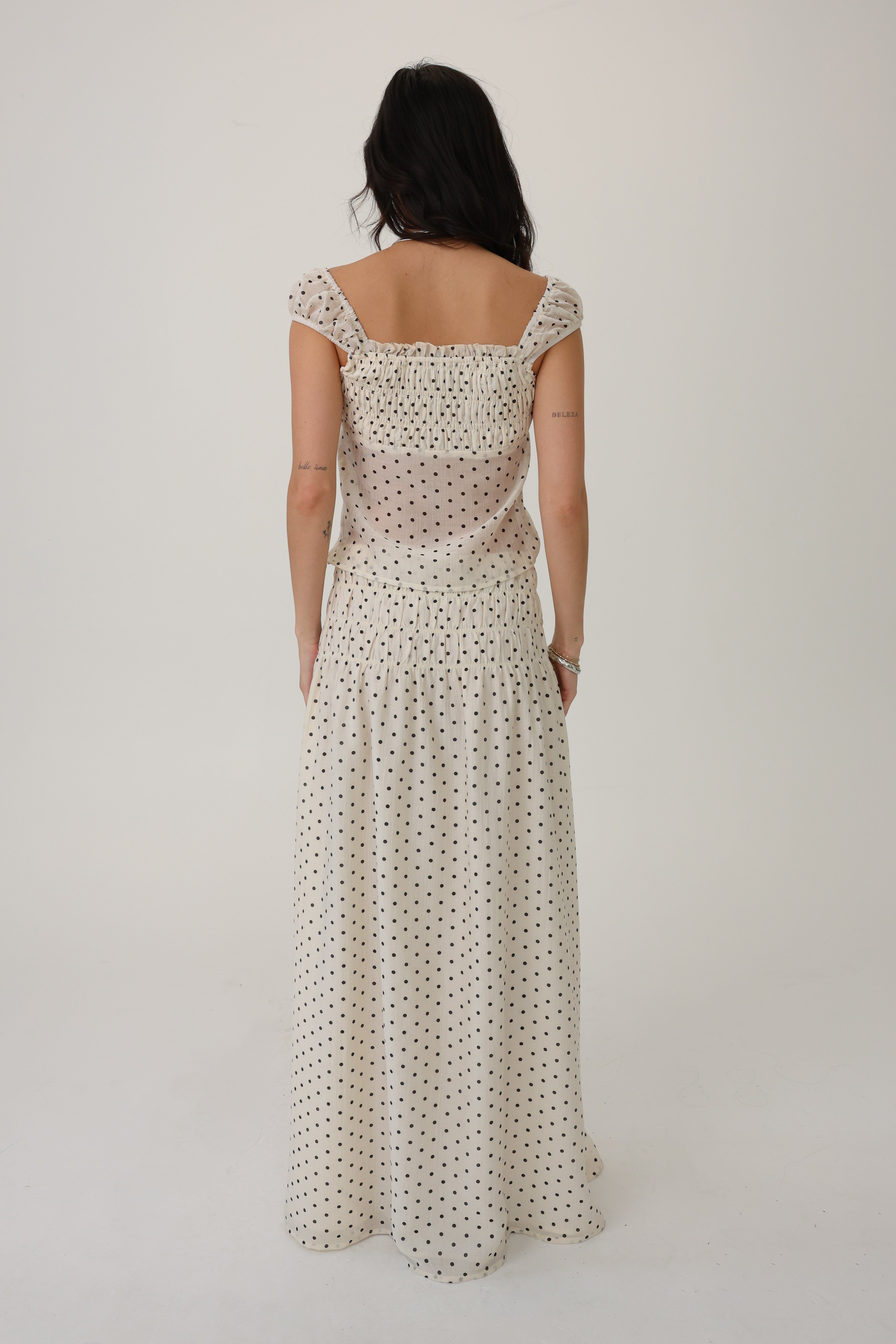 Woman wearing a long, patterned set against a plain background