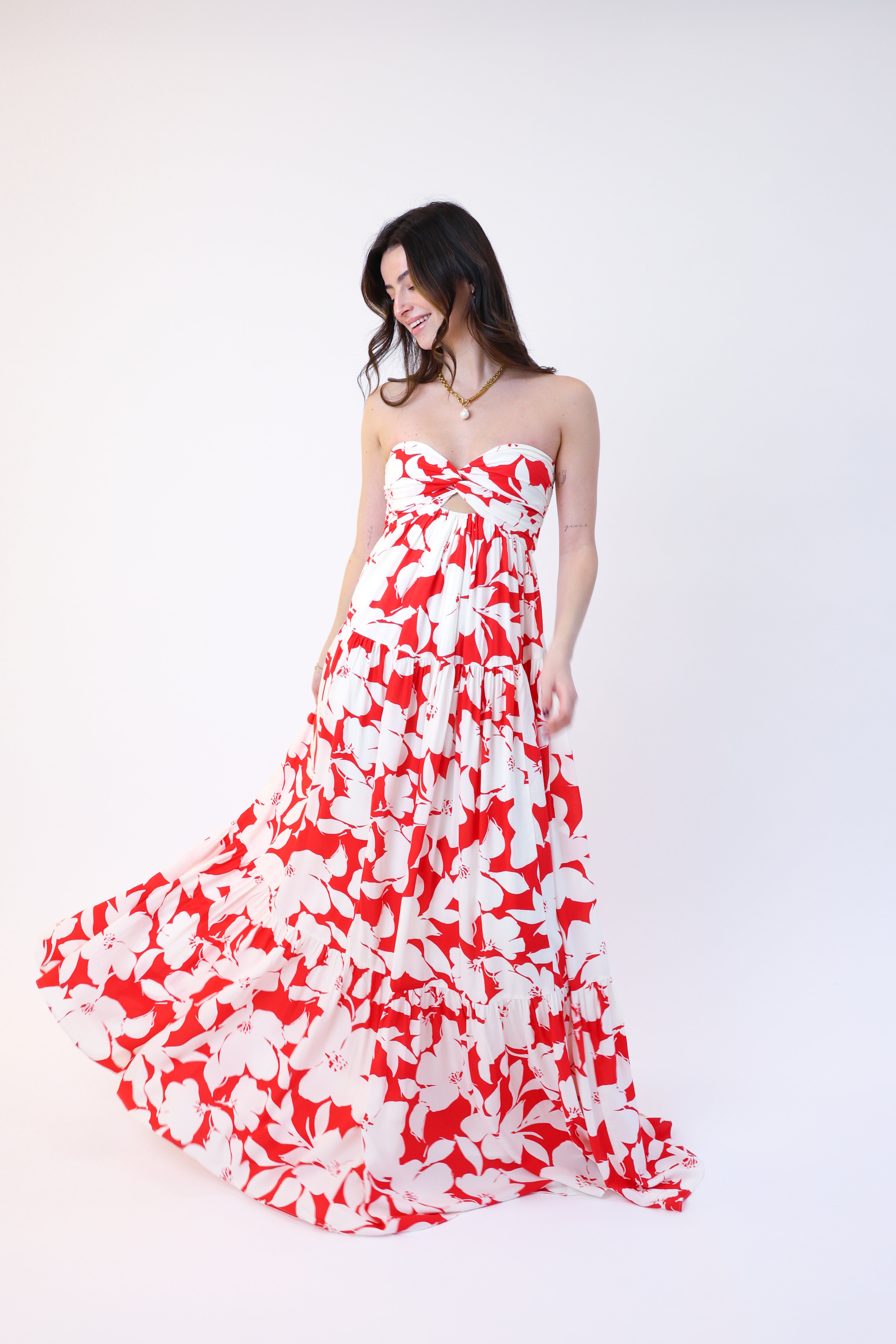 Woman wearing a strapless red and white floral dress on a white background