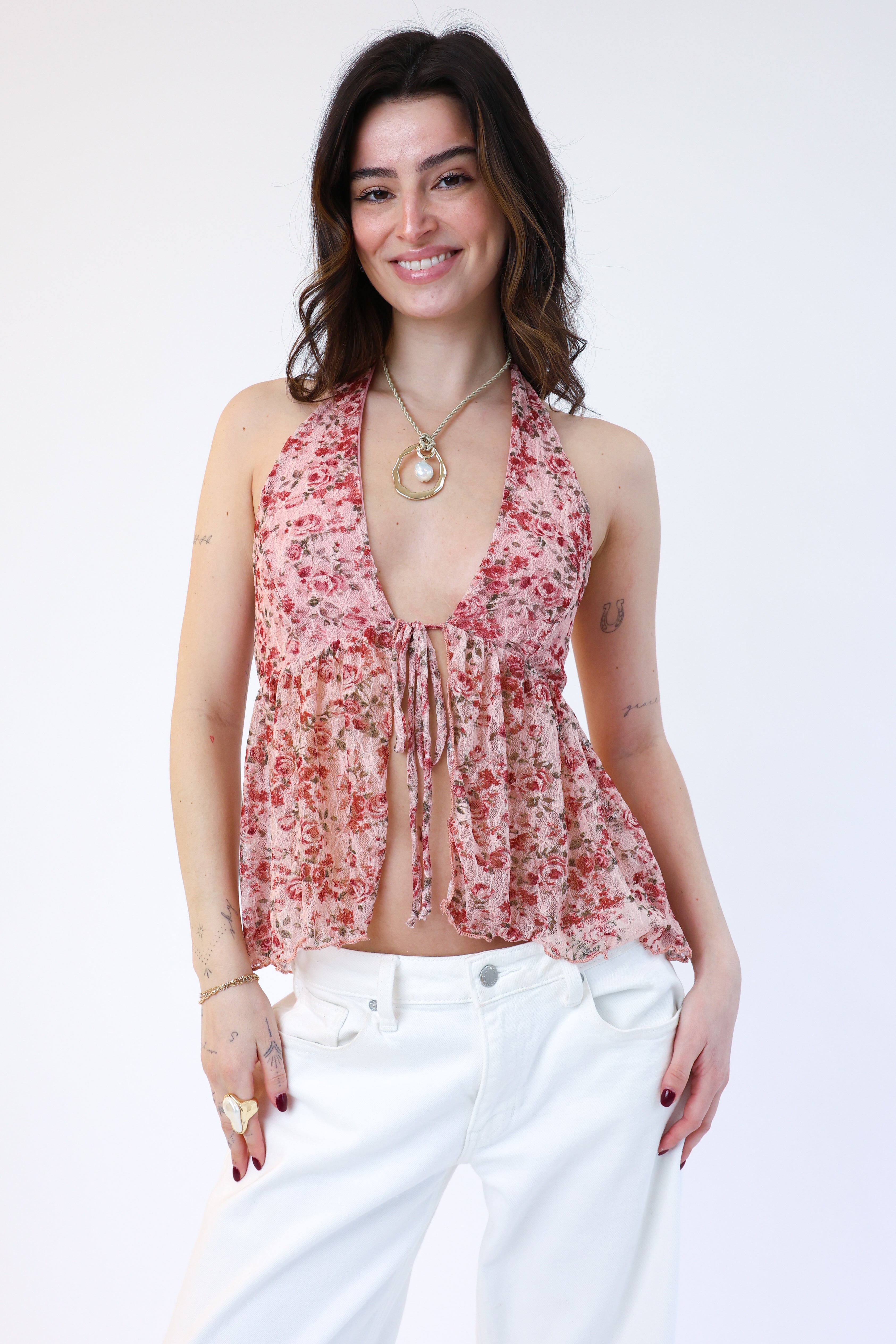 Woman wearing a floral halter top and white pants on a white background