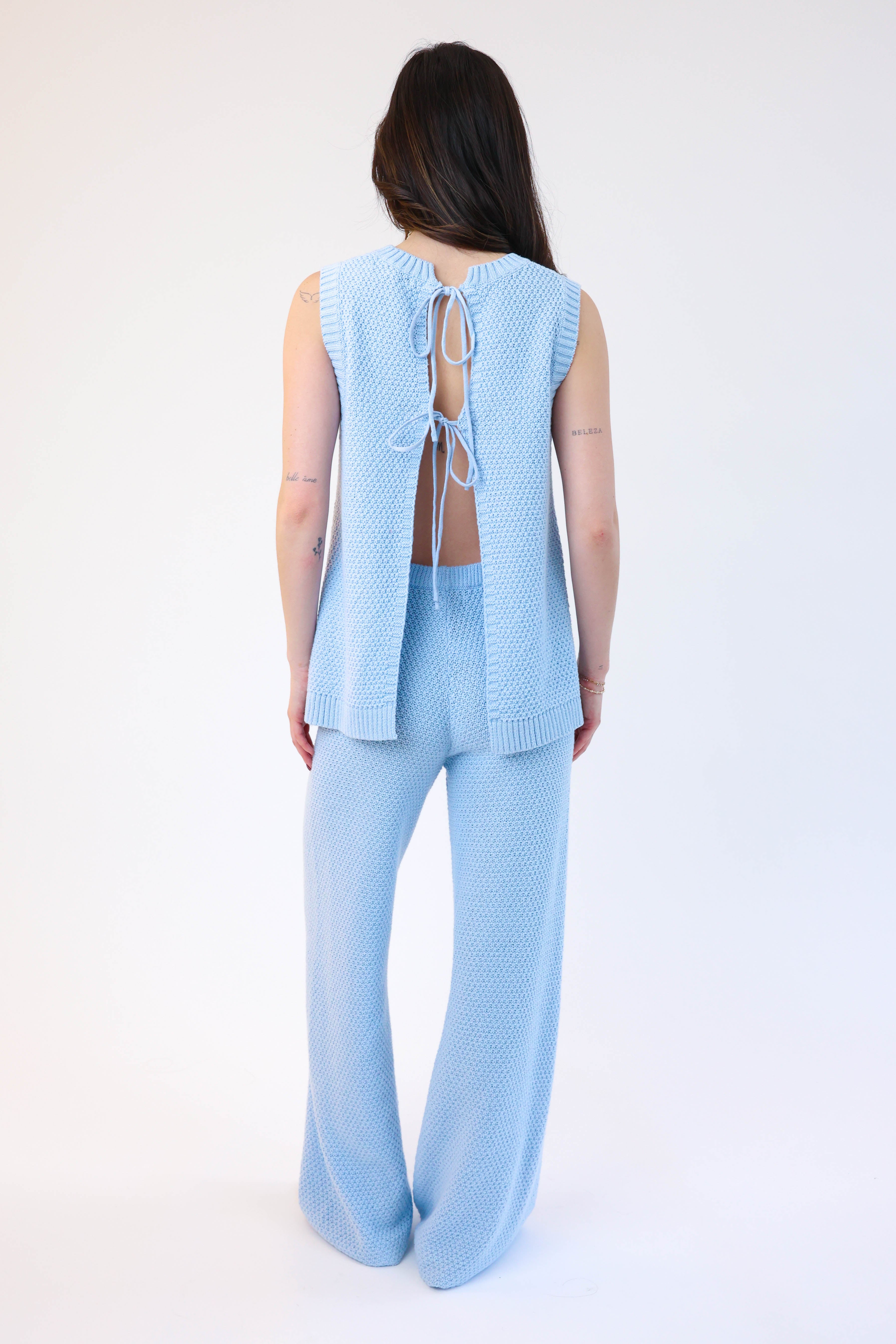 Woman wearing a light blue sleeveless top and pants set on a white background