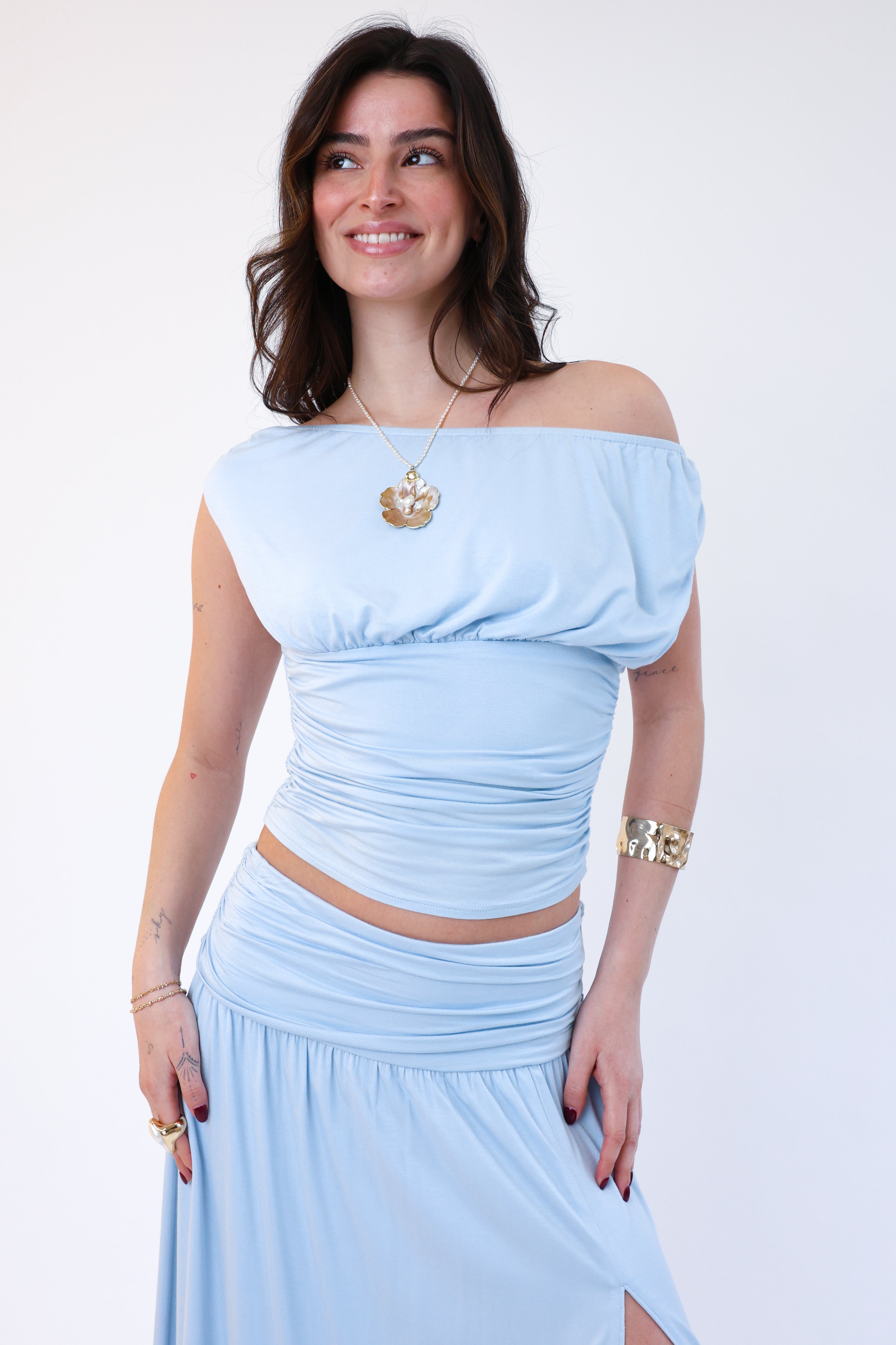 Woman wearing a light blue off-shoulder top and skirt set on a white background