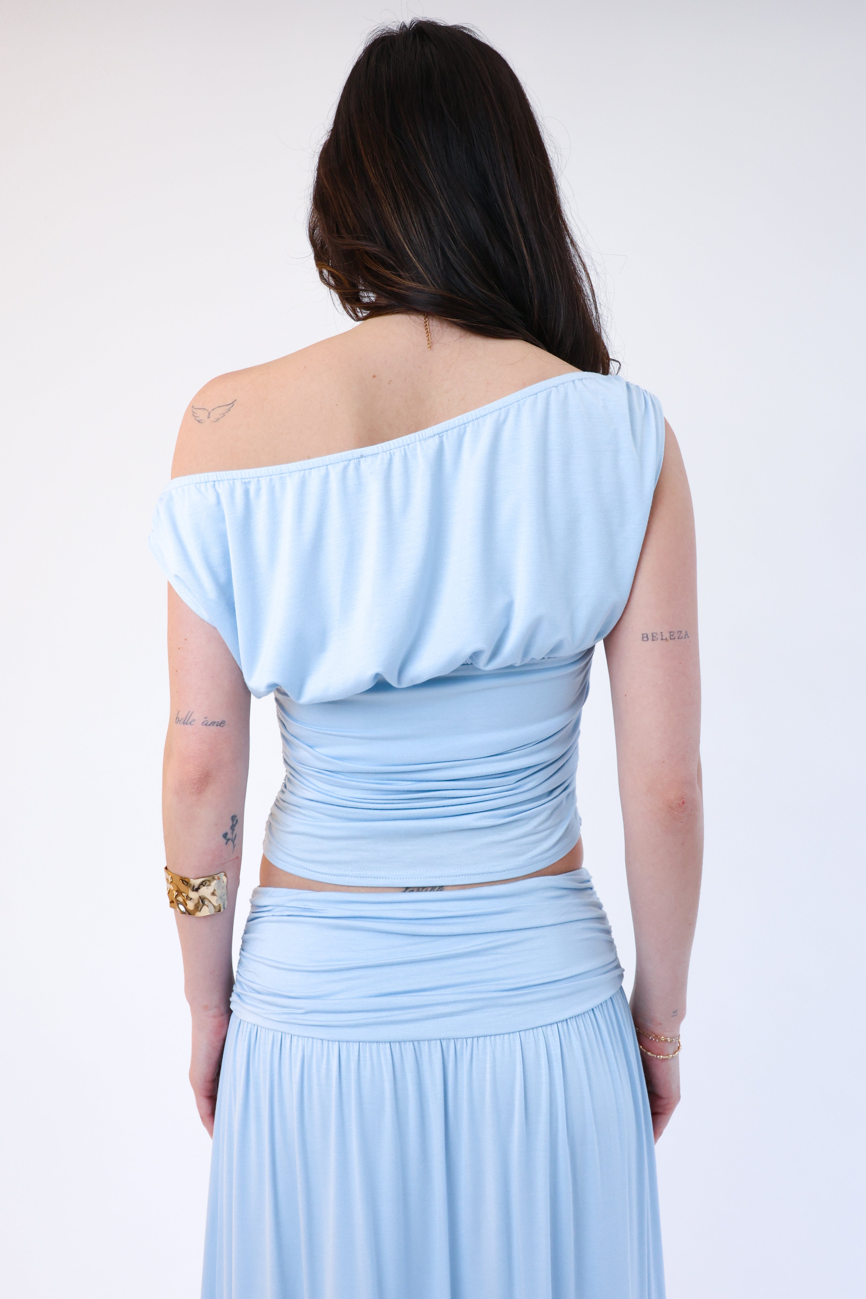 Woman wearing a light blue off-shoulder top and skirt set on a white background