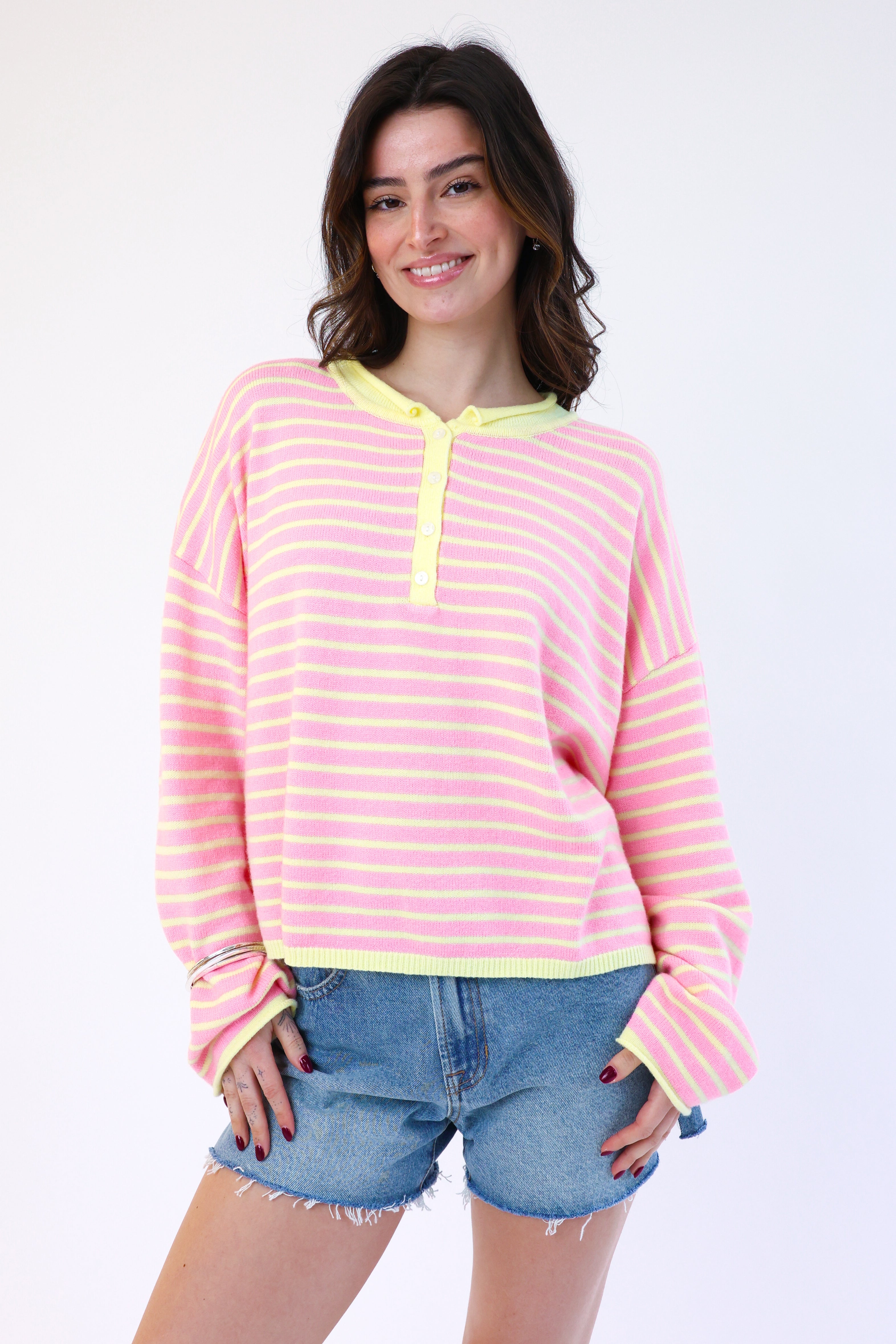 Woman wearing a pink and yellow striped shirt with denim shorts on a white background