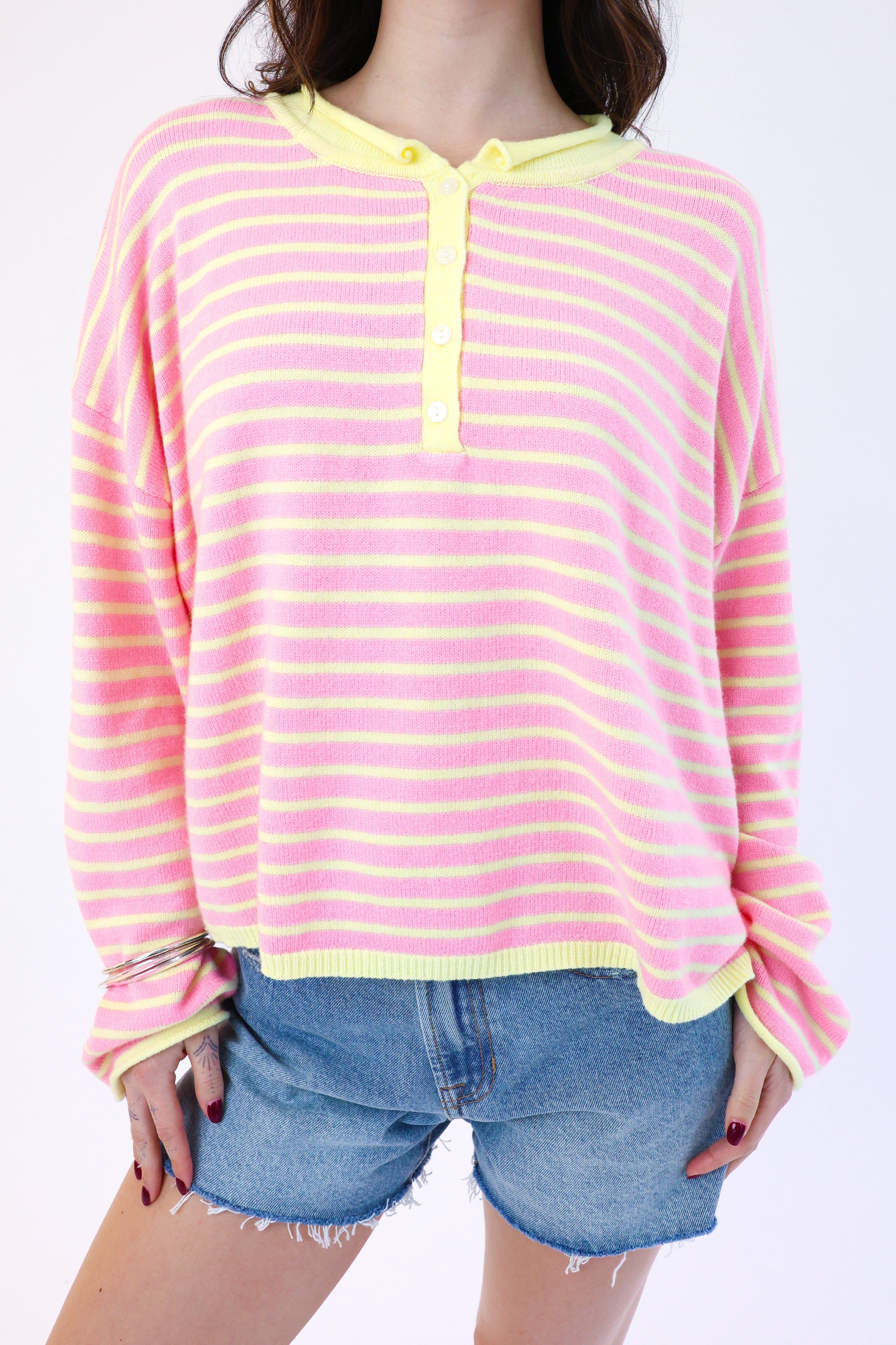 Person wearing a pink and yellow striped shirt with denim shorts on a white background