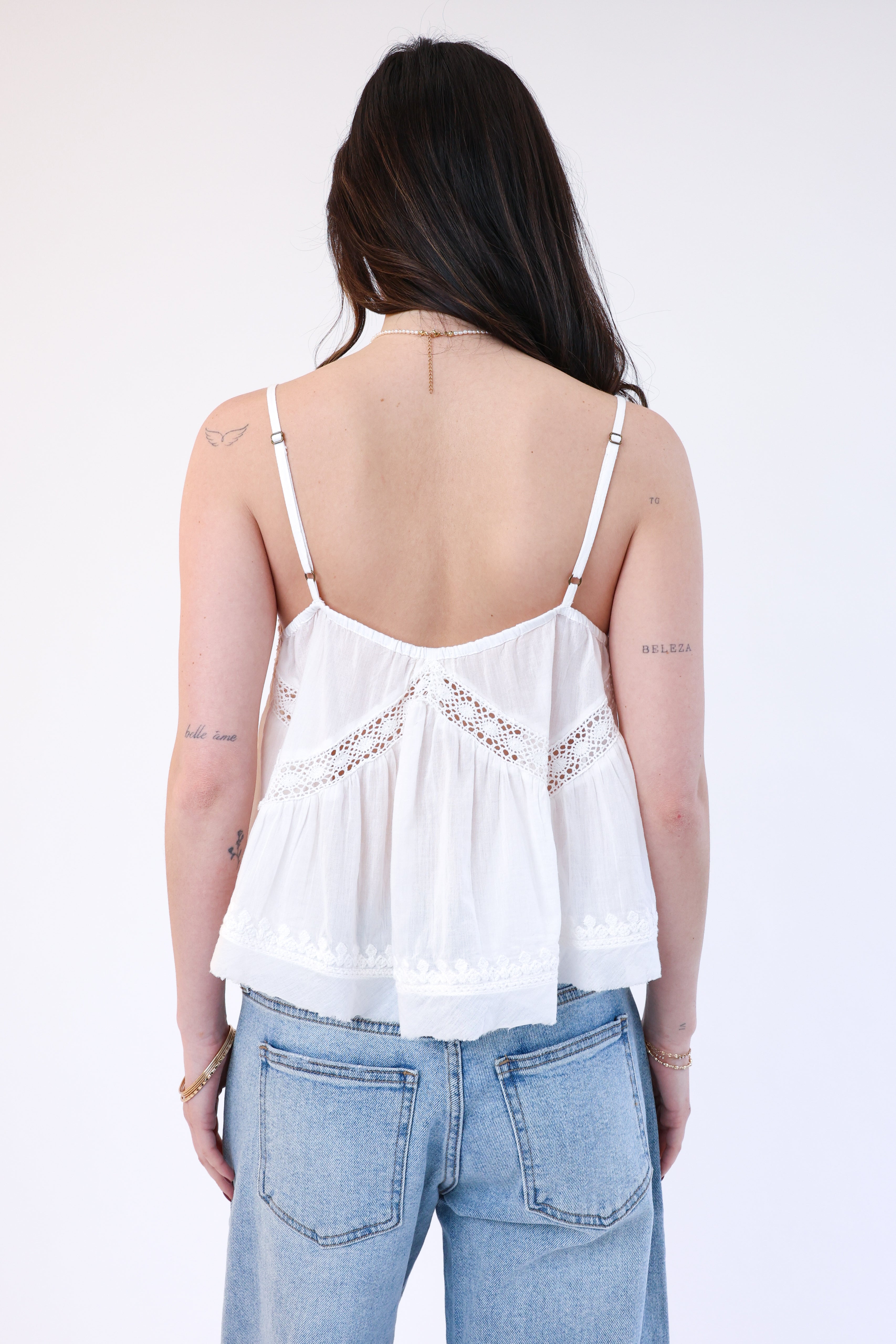 Person wearing a white lace top and blue jeans on a white background
