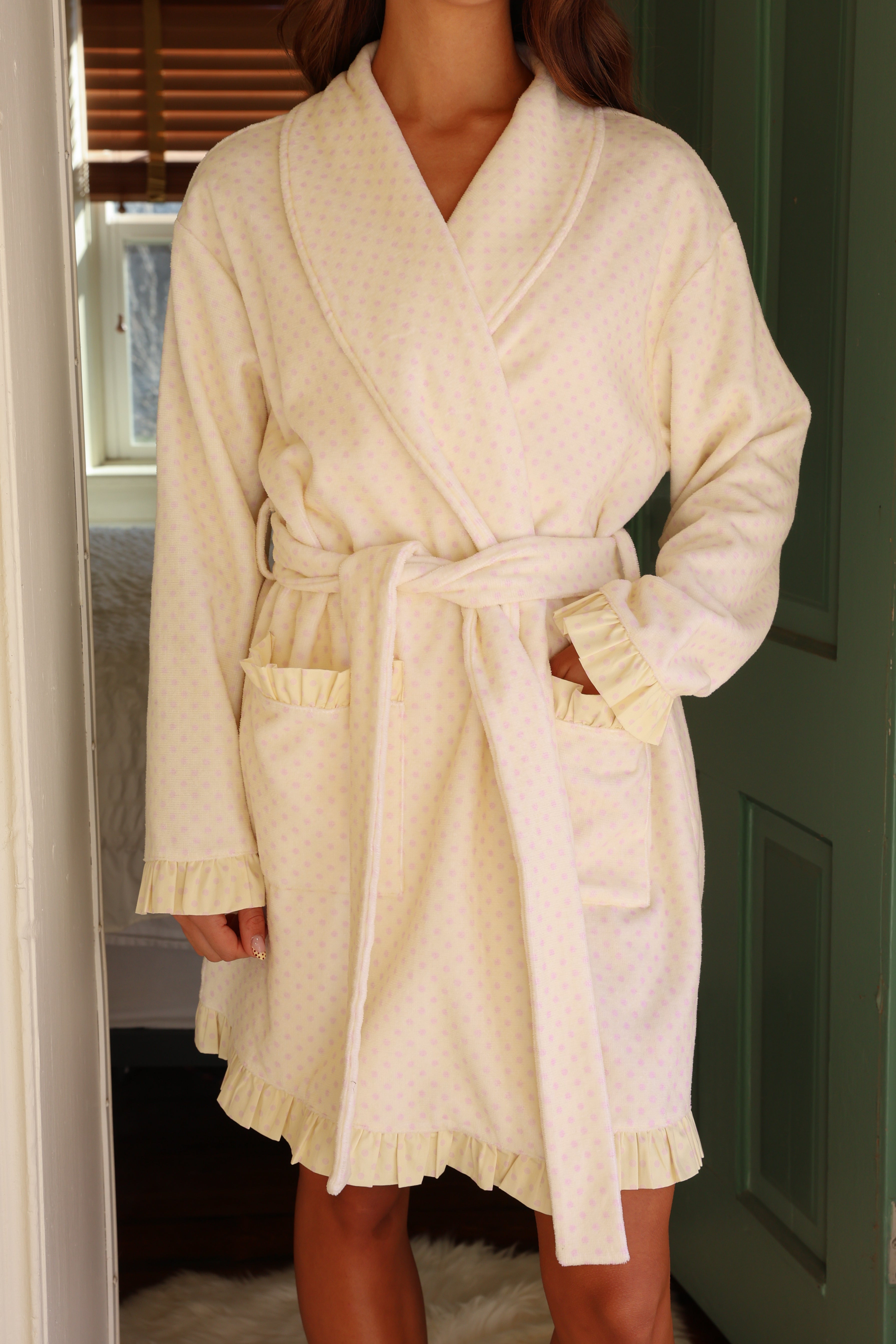 Person wearing a cream-colored robe standing in a doorway.