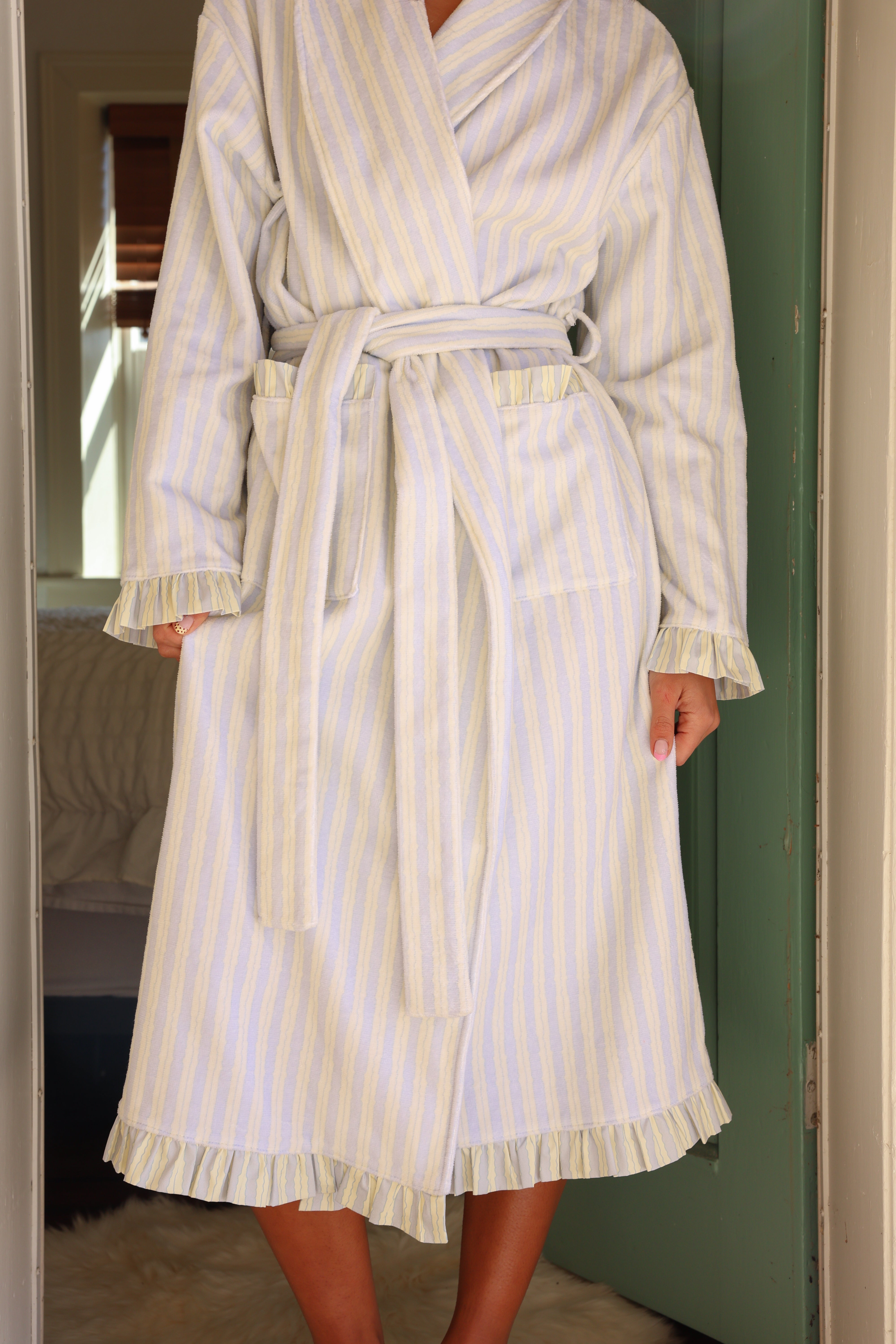 Person wearing a white and blue striped robe in a room.