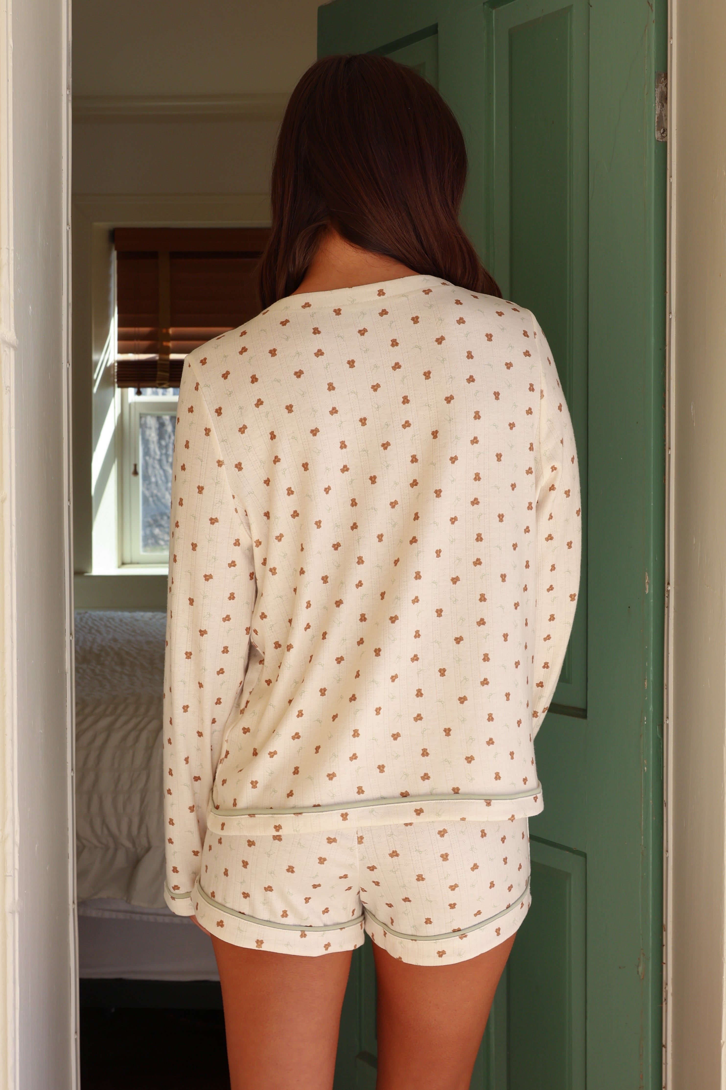 Person wearing a patterned pajama set standing in a doorway.