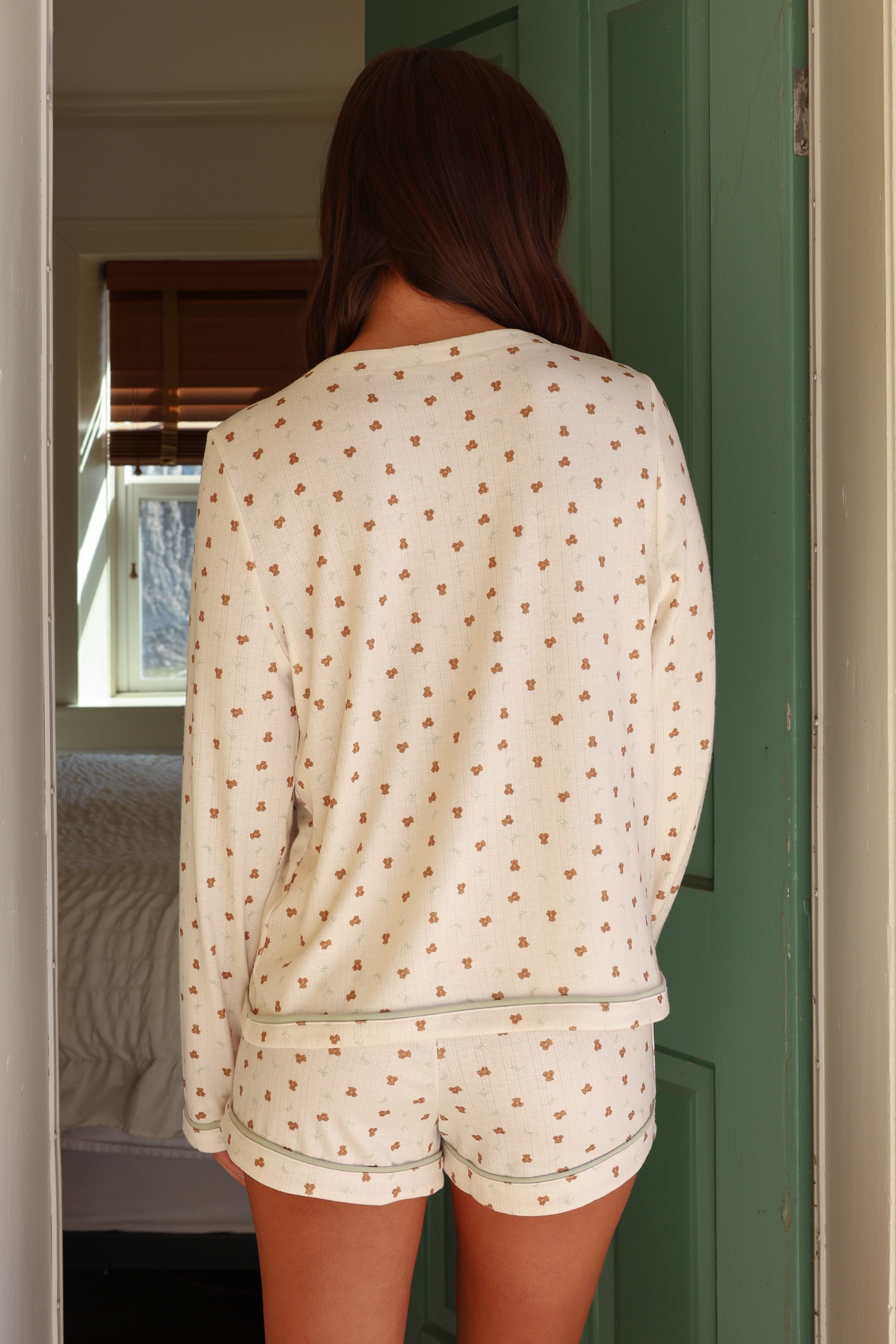 Person wearing a patterned pajama set standing in a doorway.