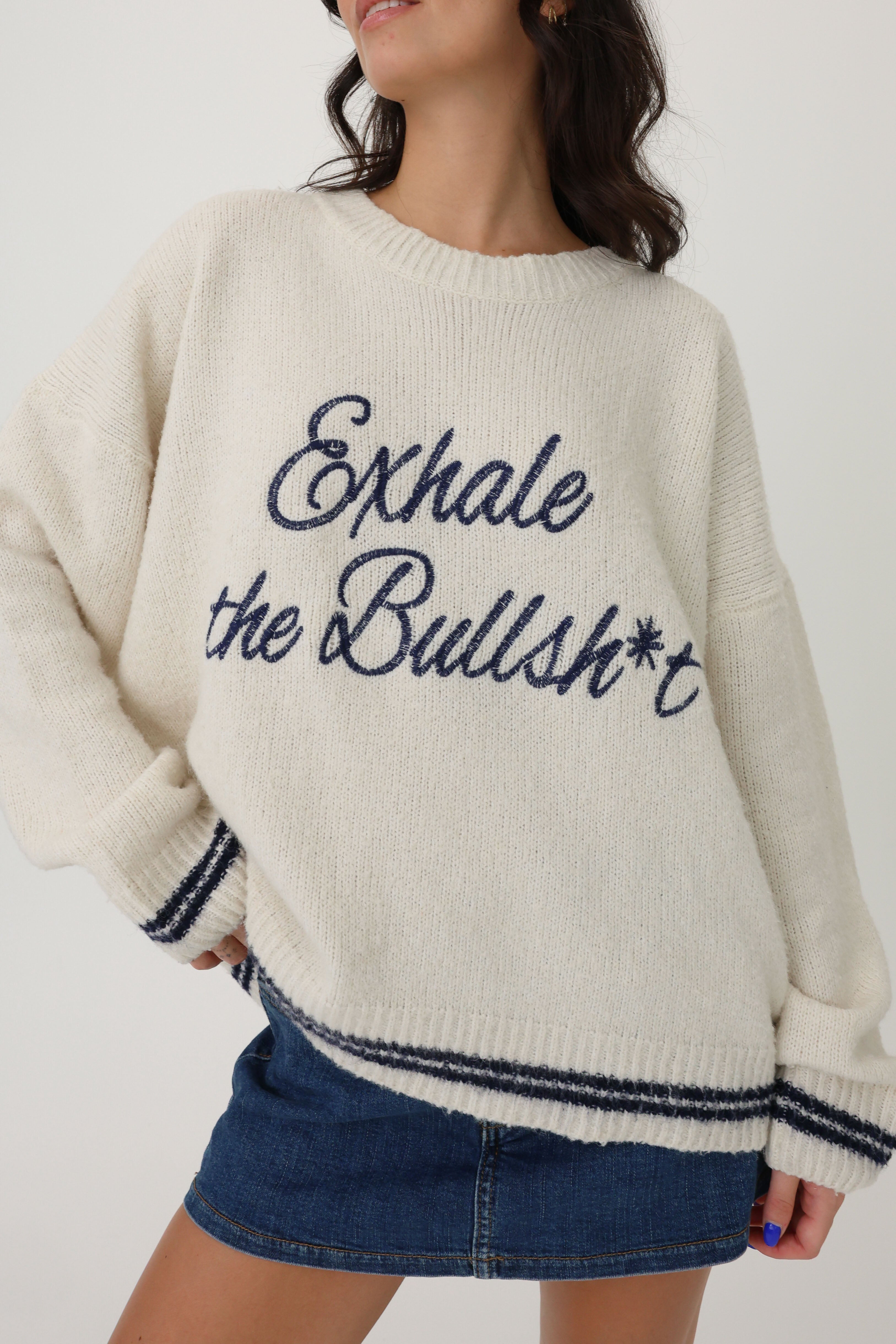 Person wearing a sweater with text and denim skirt on a plain background