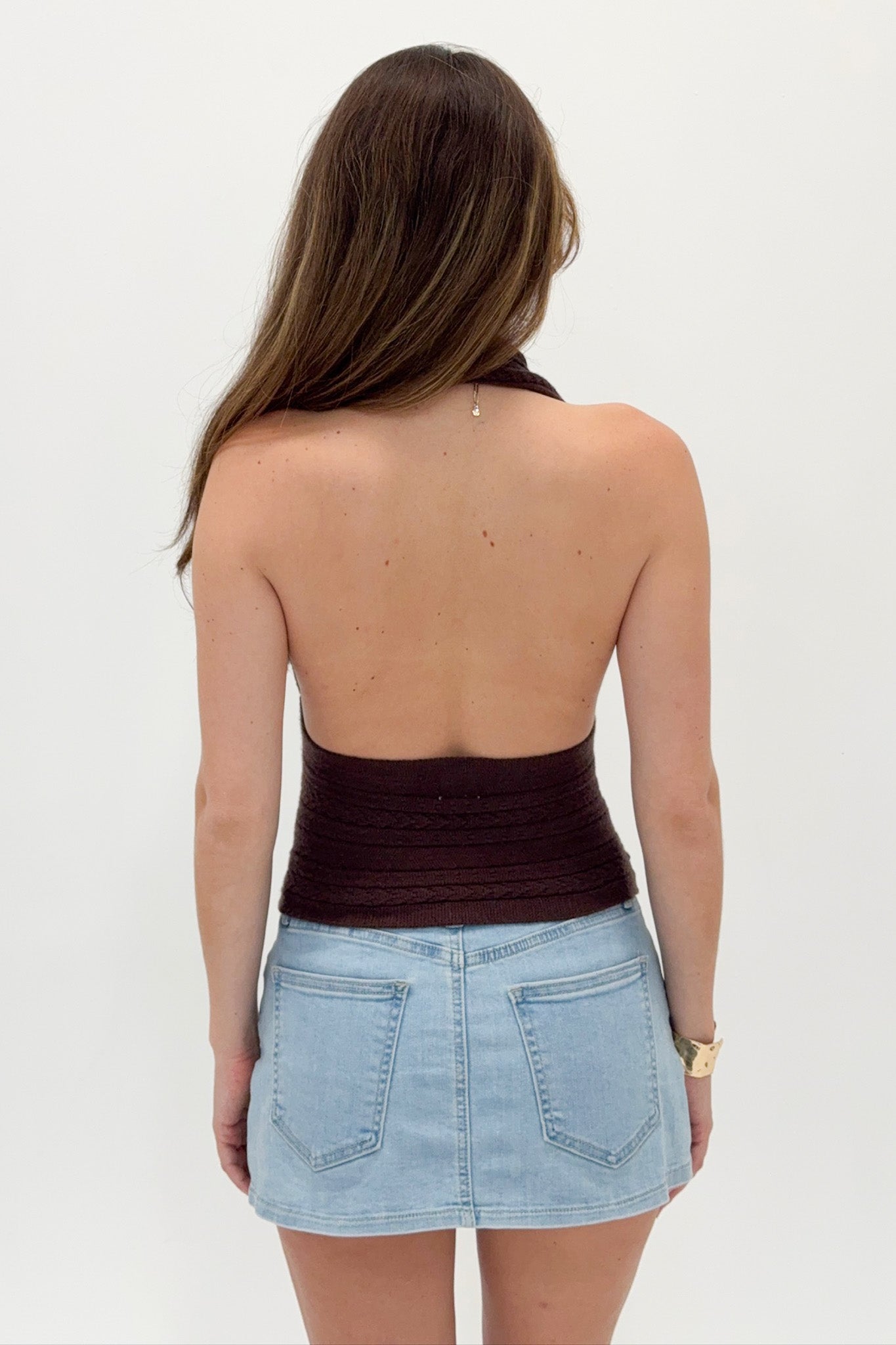 Woman wearing a brown strapless top and light blue denim skirt on a white background
