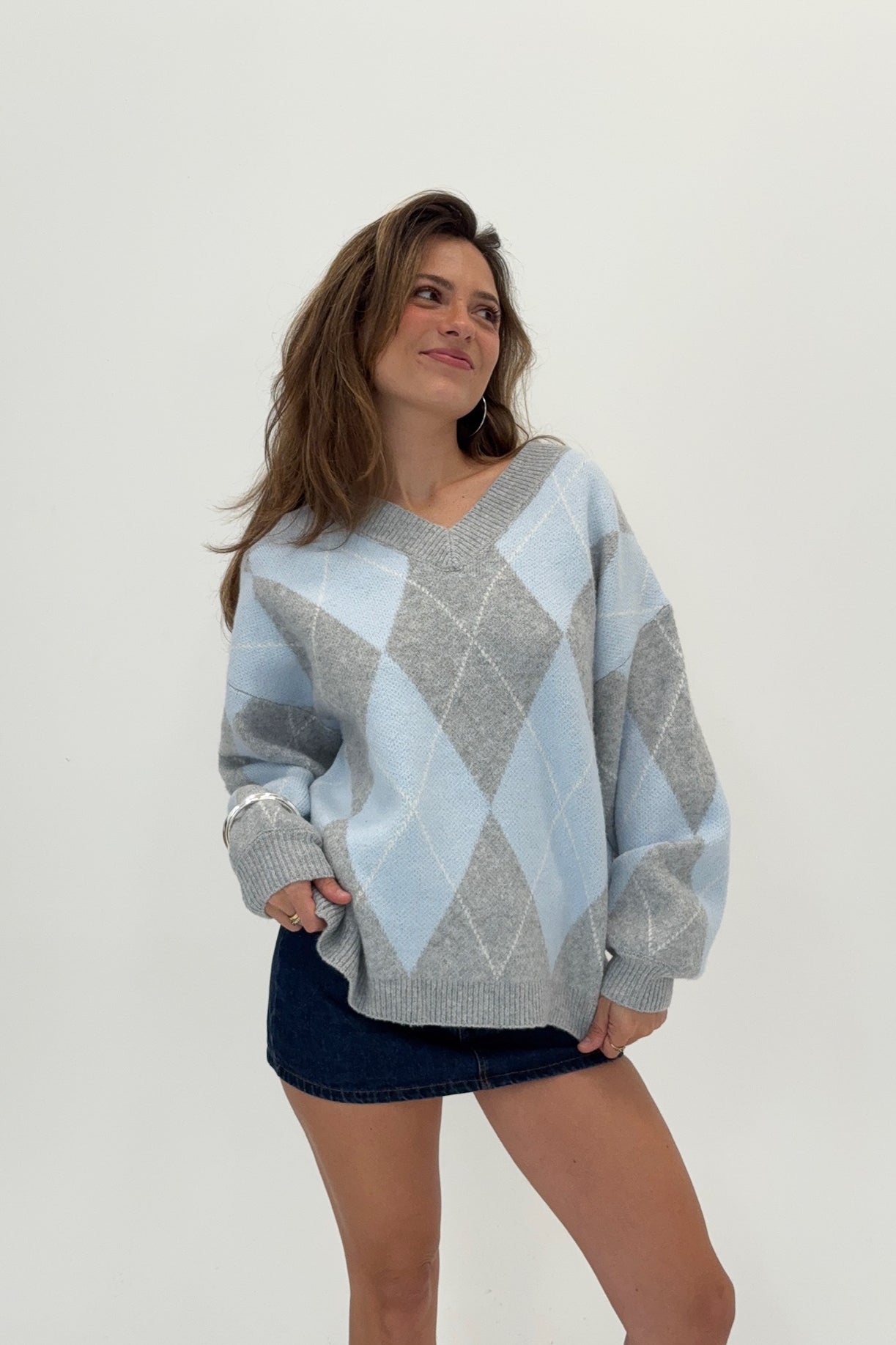 Woman wearing a blue and gray argyle sweater on a white background