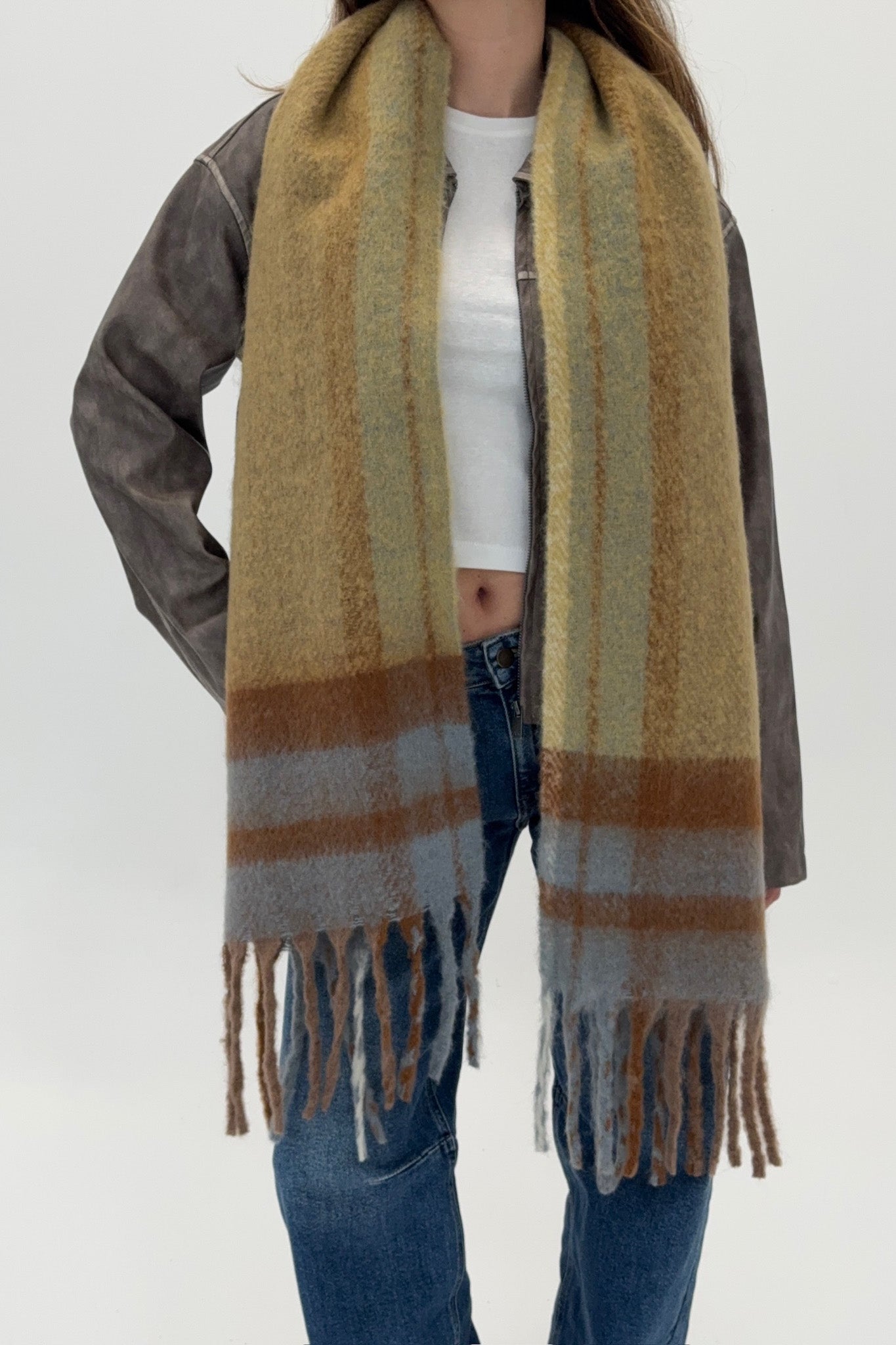 Person wearing a striped scarf with fringes on a white background