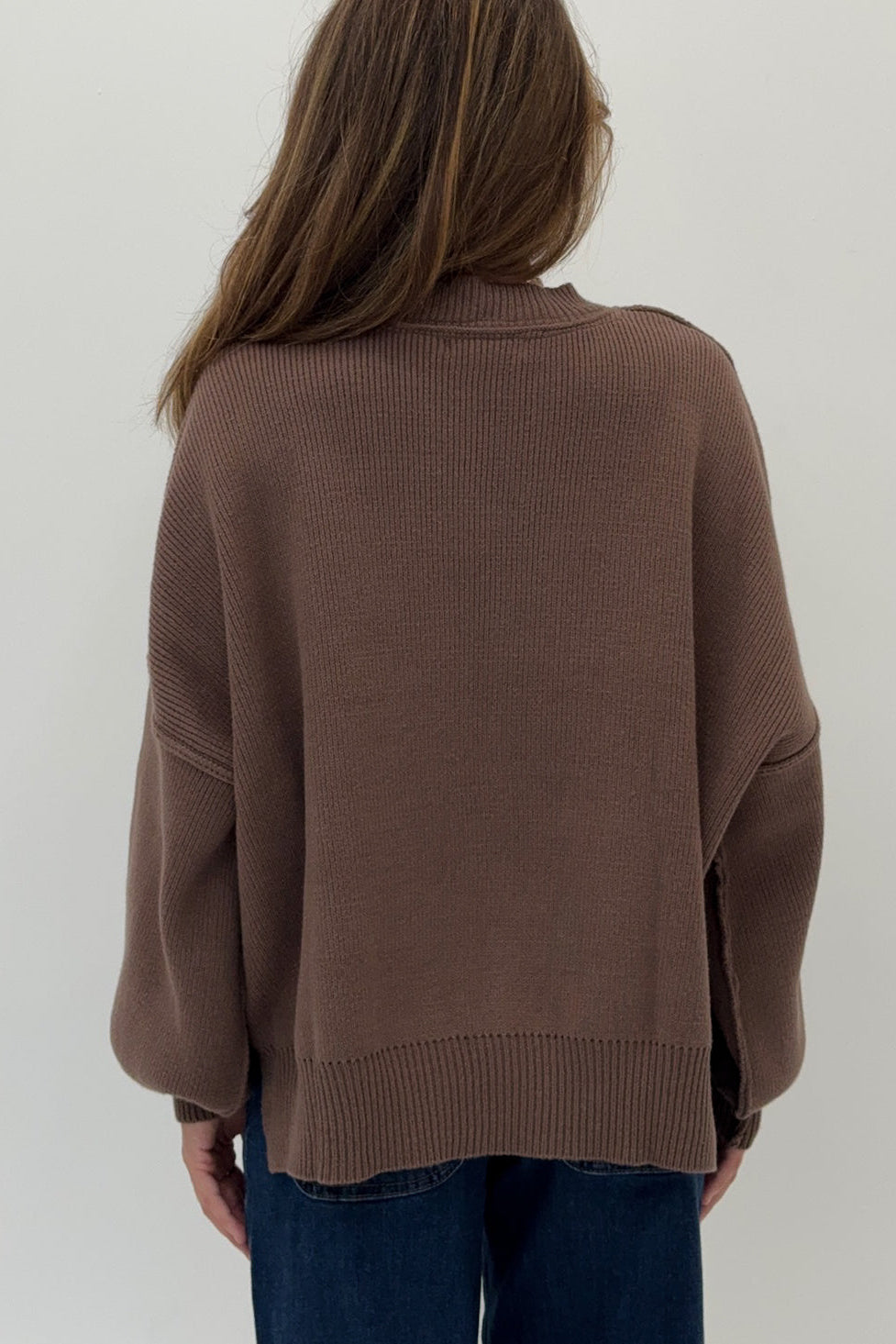Person wearing a brown sweater against a white background