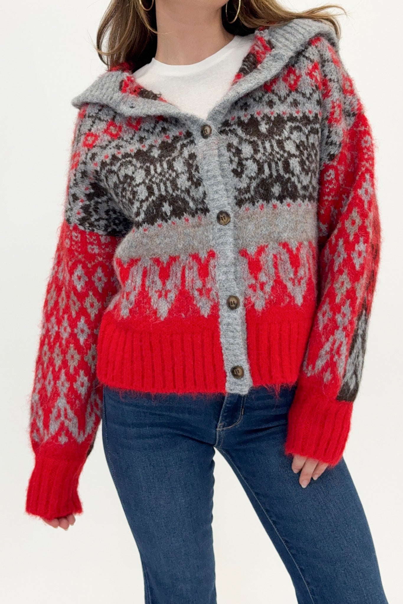 Person wearing a red and gray patterned hoodie with blue jeans on a white background