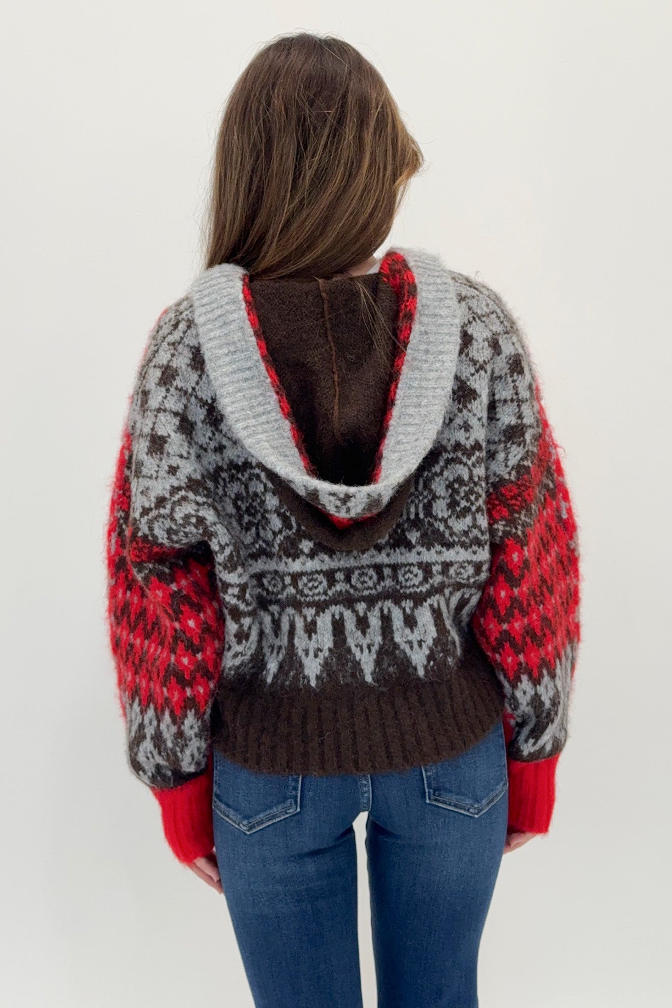 Person wearing a patterned sweater with red, gray, and brown colors on a white background