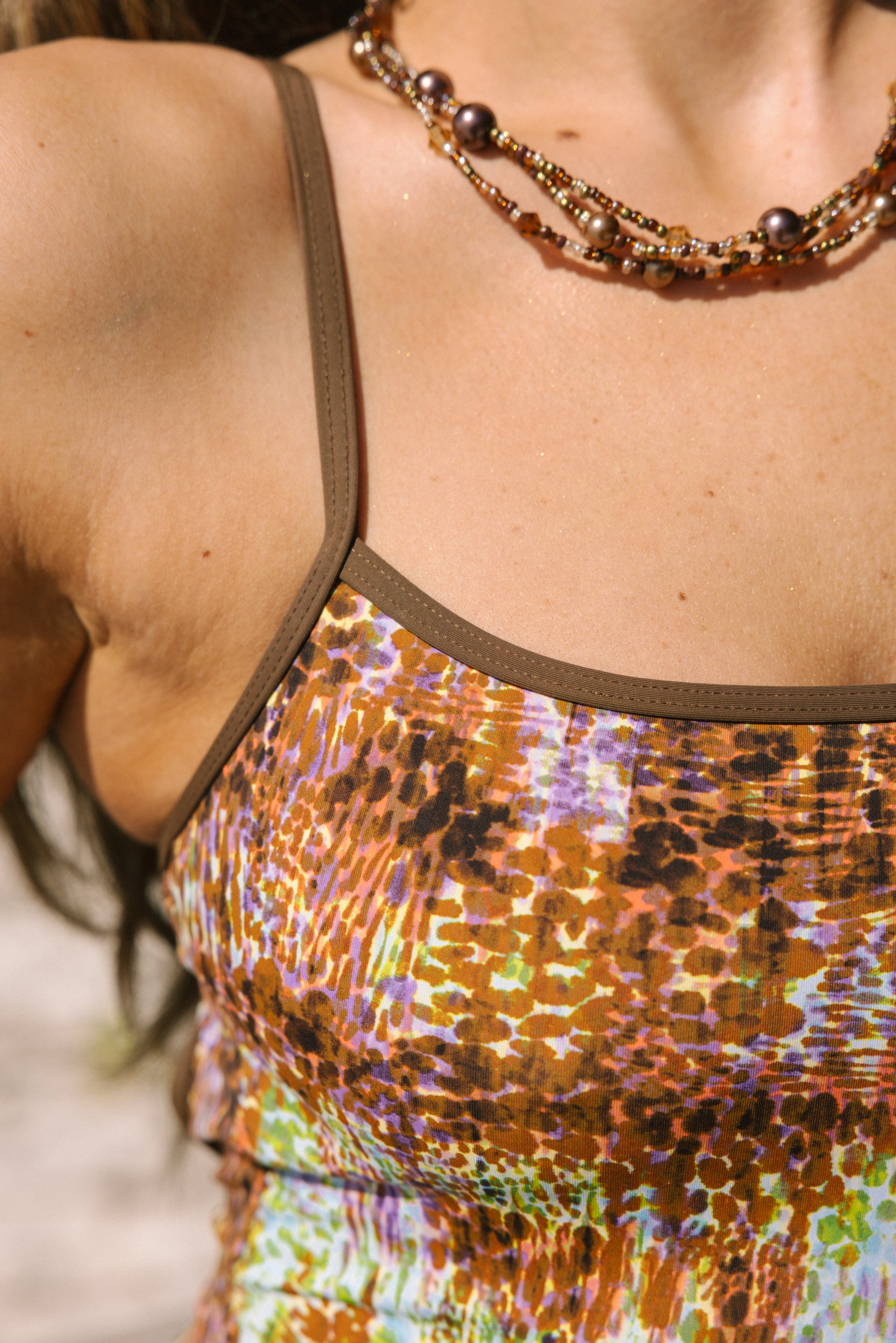 Close-up of a person wearing a multicolored sequin top and a beaded necklace.