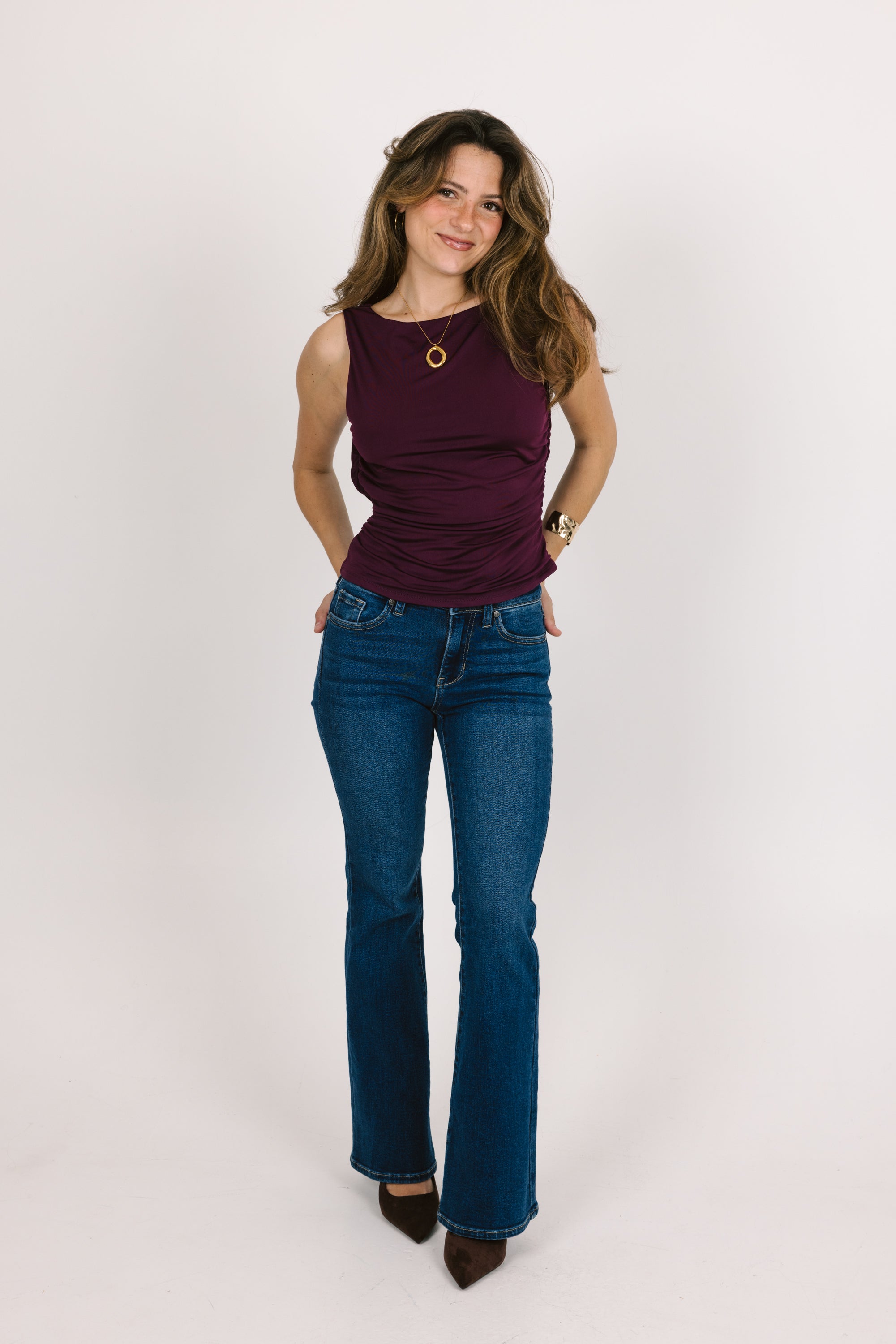 Woman wearing a purple top and blue jeans on a white background