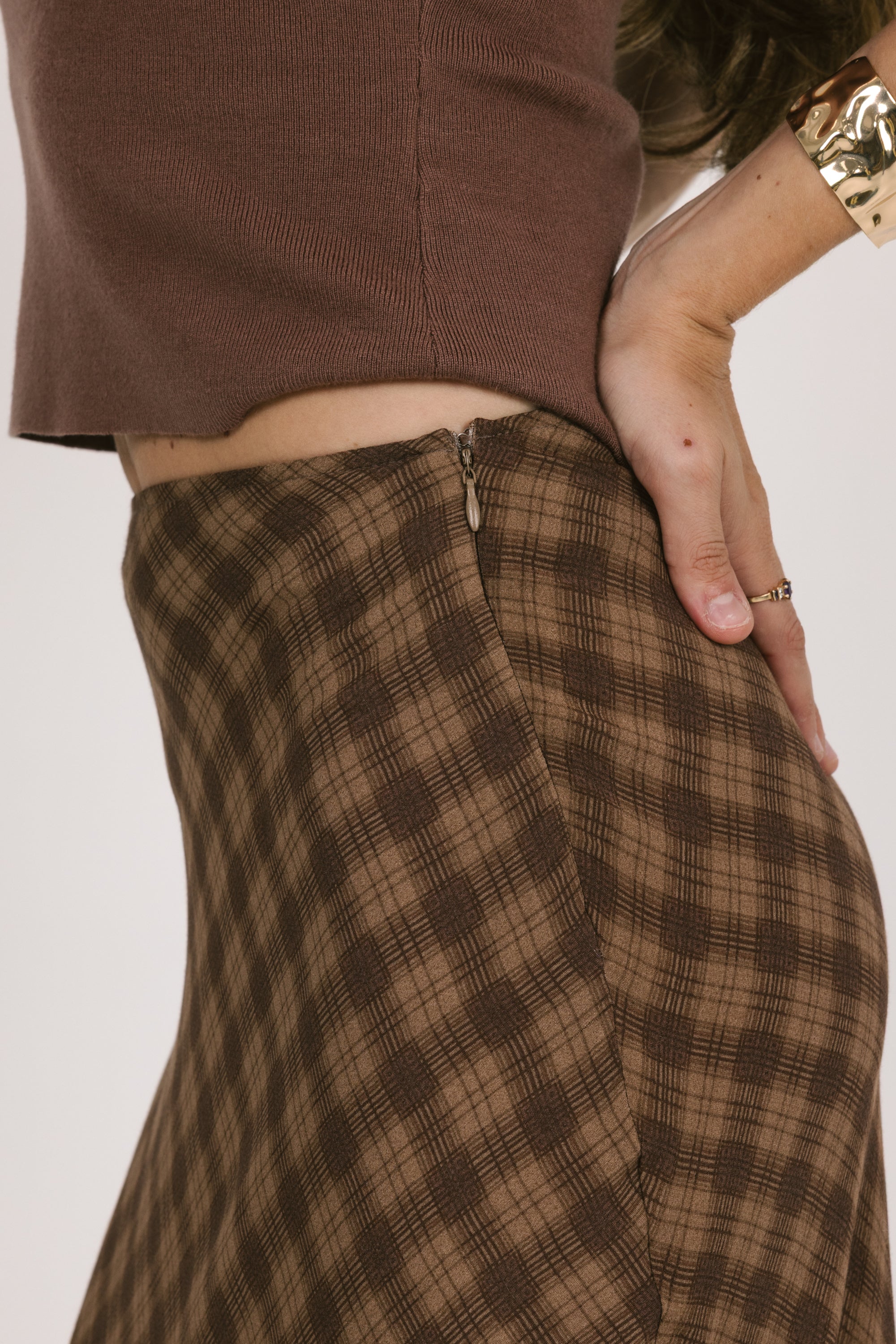 Brown plaid skirt worn by a person on a plain background