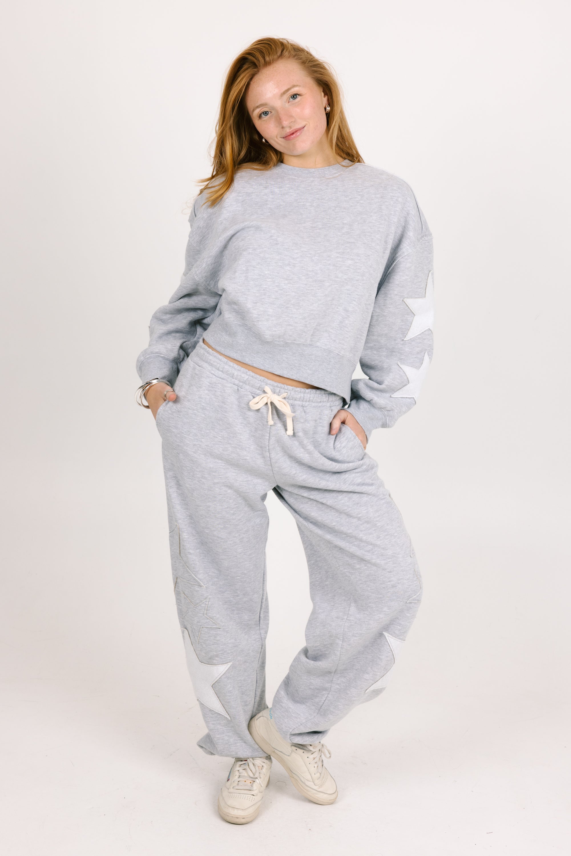 Woman wearing a gray sweatshirt and pants set on a white background