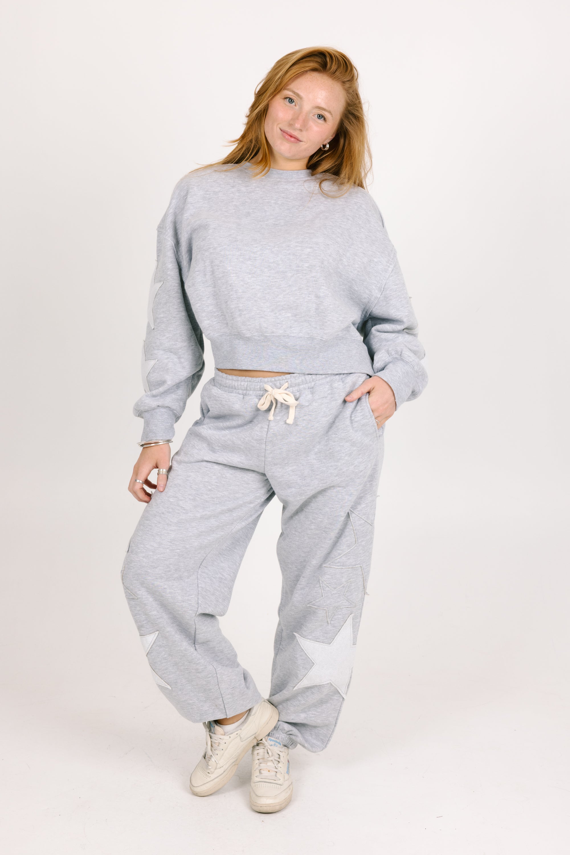 Woman wearing a gray sweatshirt and pants set on a white background