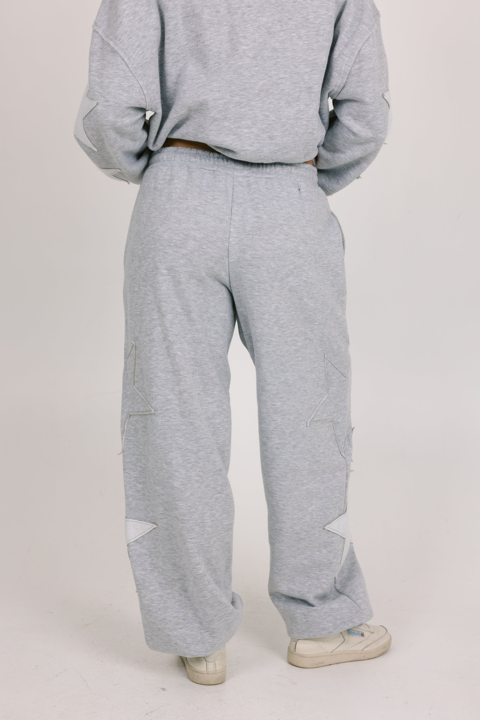 Person wearing a gray sweatshirt and pants on a plain background