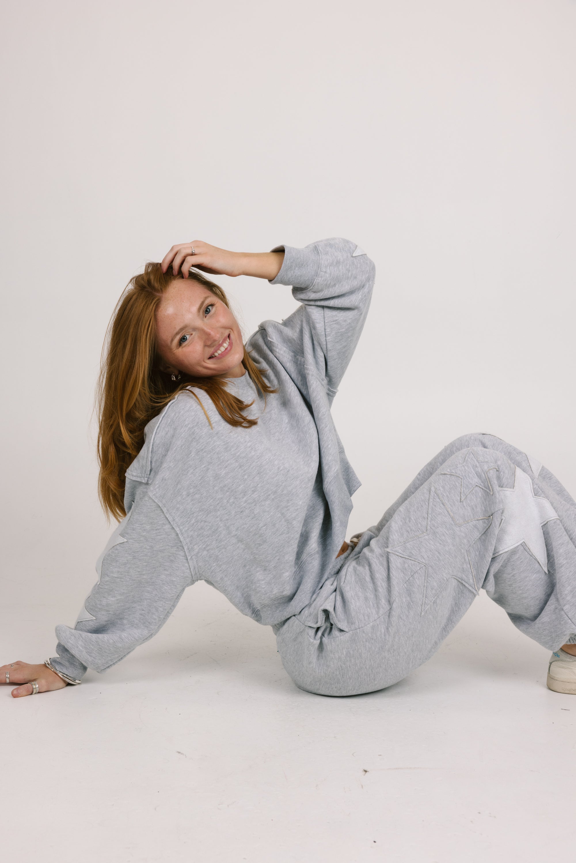 Woman wearing a gray tracksuit sitting on a white background