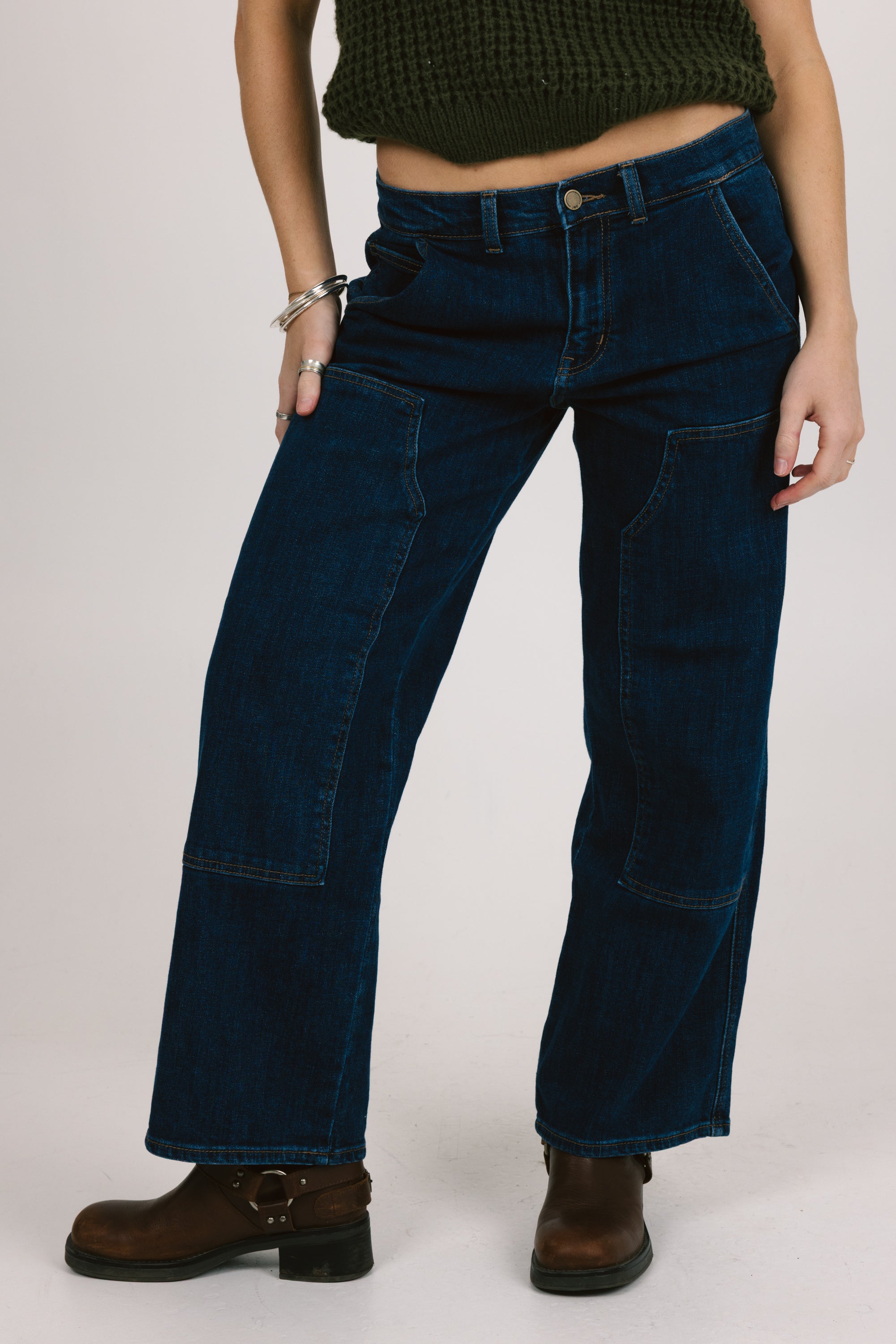Person wearing dark blue jeans on a plain background