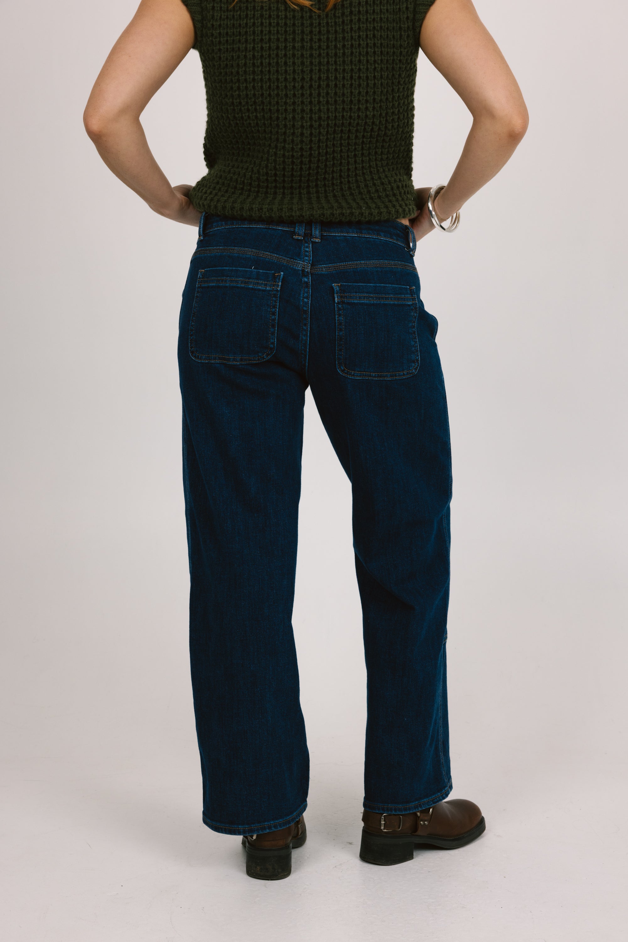 Person wearing blue jeans and a dark top on a plain background