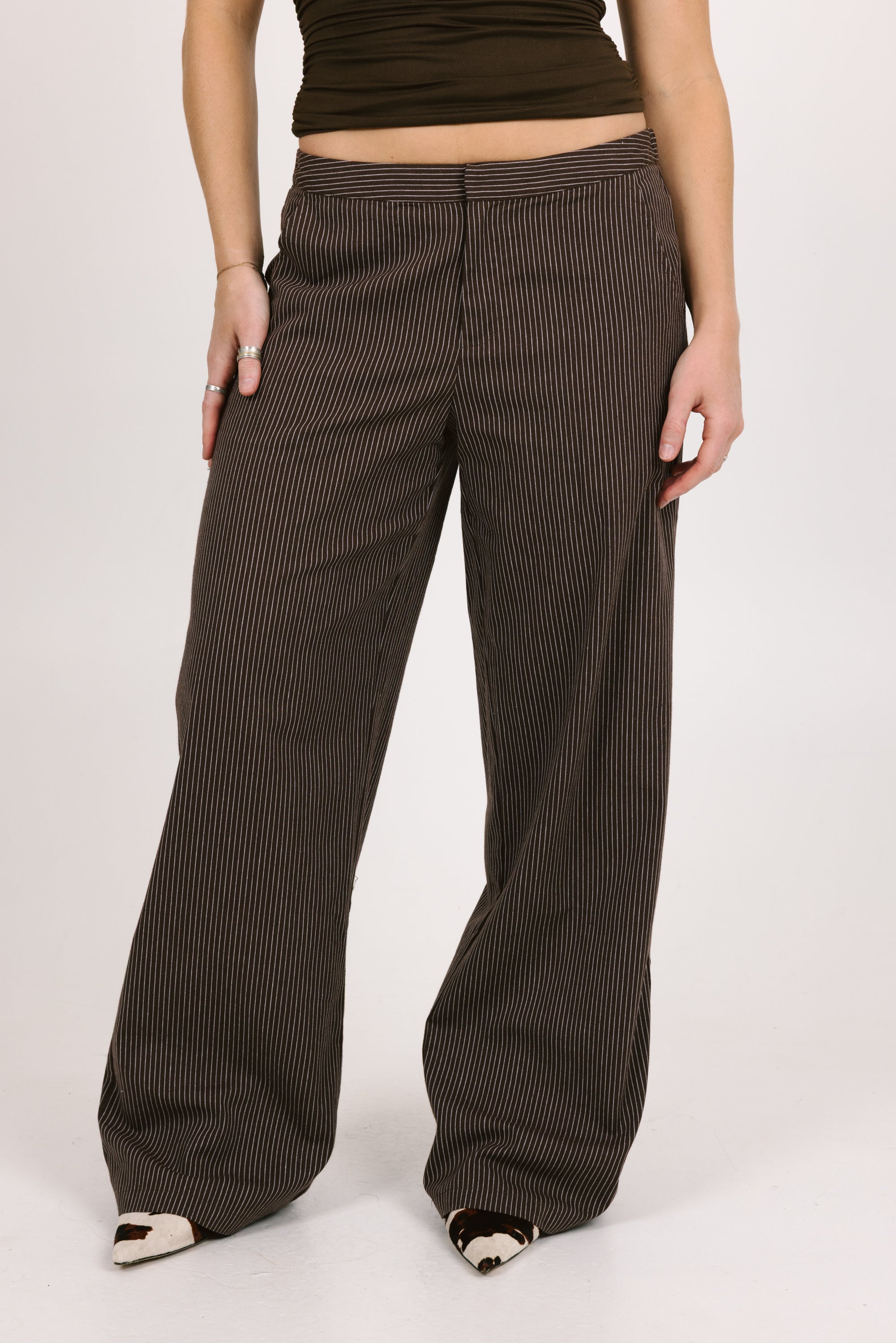 Person wearing brown pinstripe pants on a white background