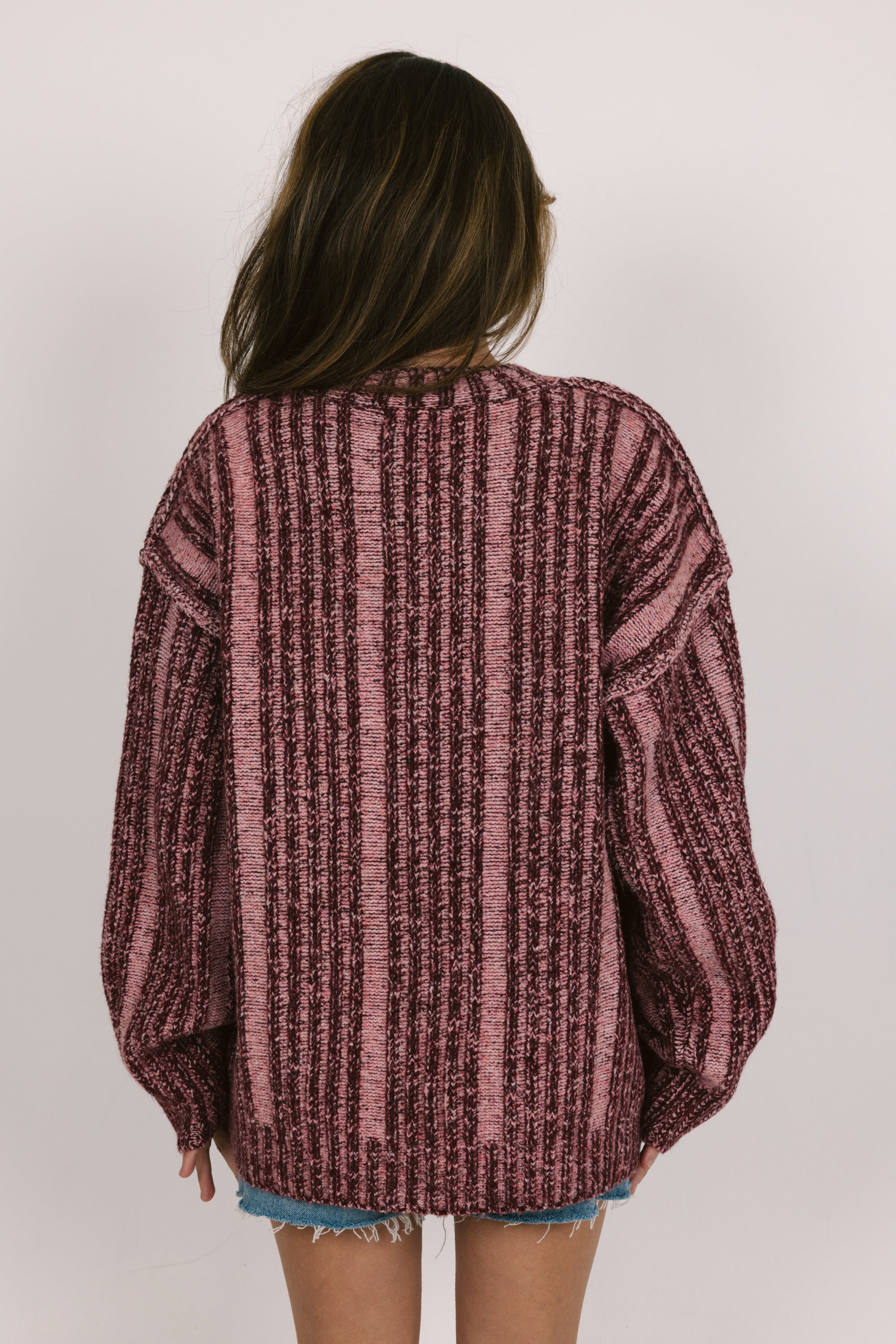 Person wearing a maroon and black striped sweater on a plain background