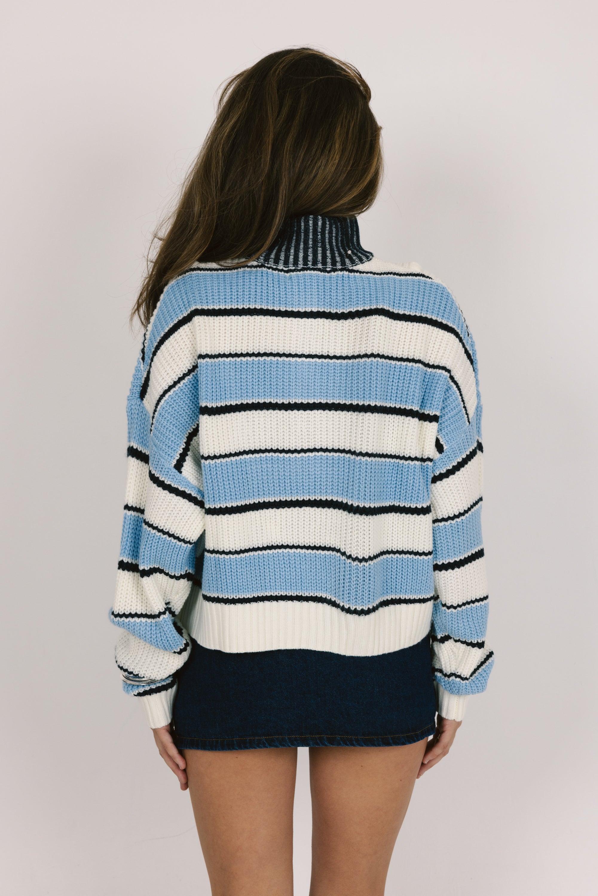 Person wearing a blue and white striped sweater with a plain background