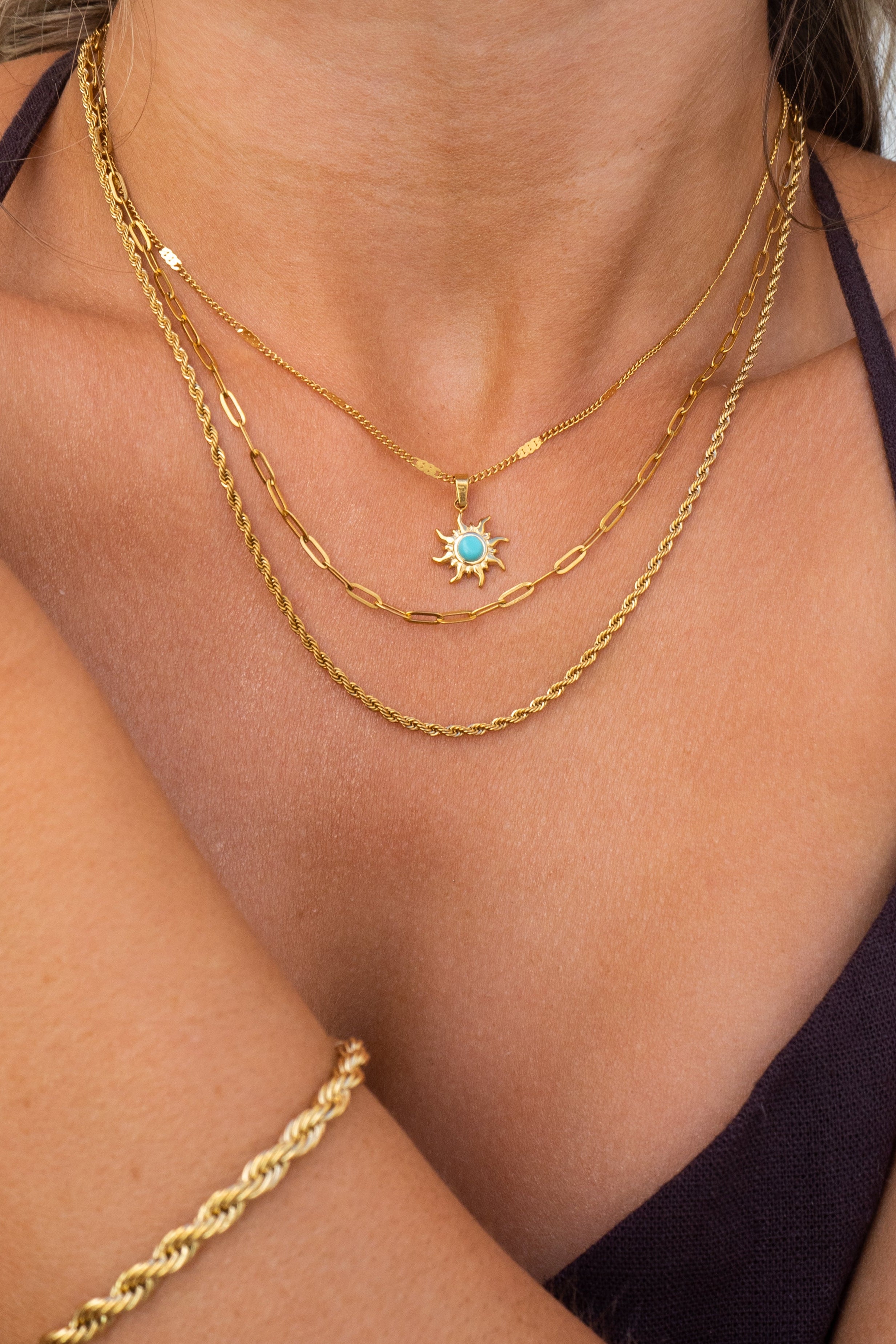 Close-up of a person wearing multiple gold necklaces with a star pendant.
