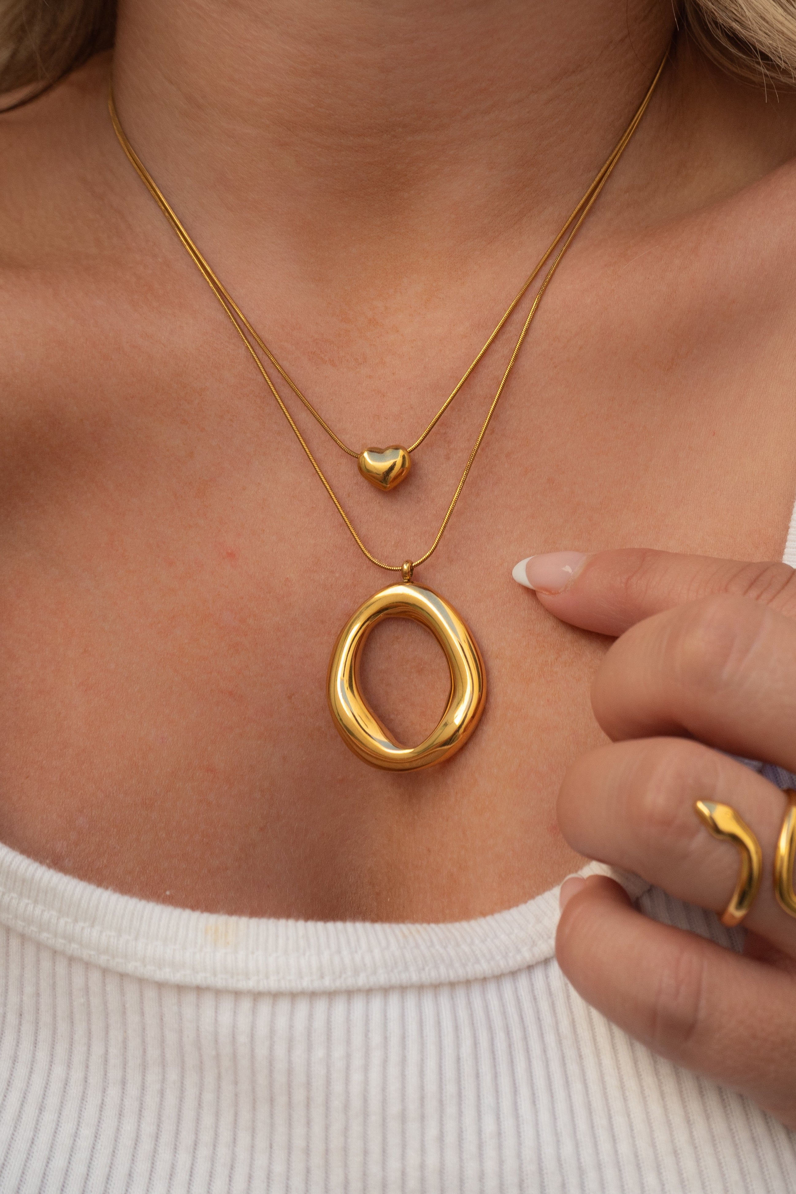Gold necklace and ring on a person wearing a white top